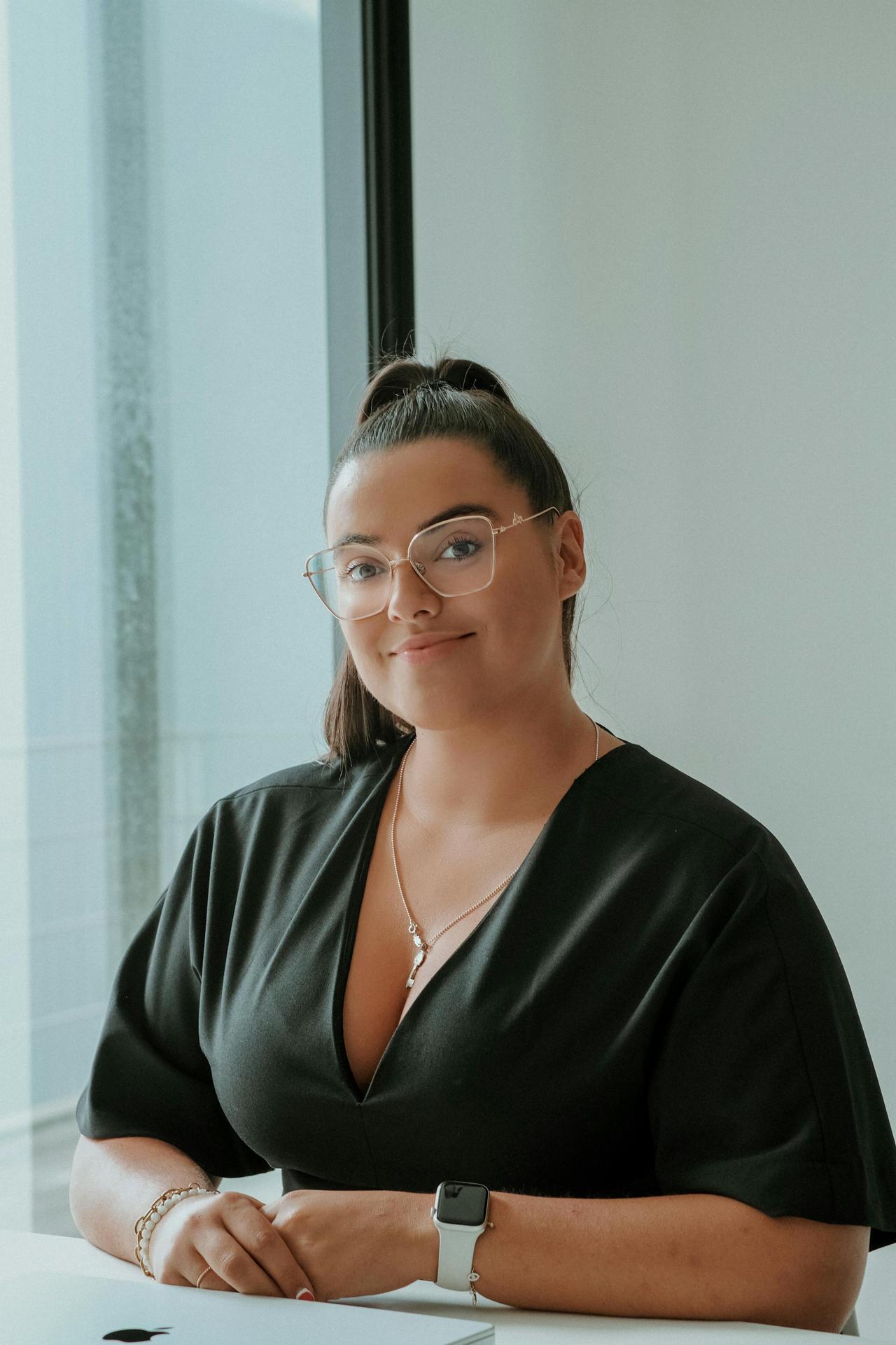 Focused businesswoman in glasses with confident smile, seated in modern office.