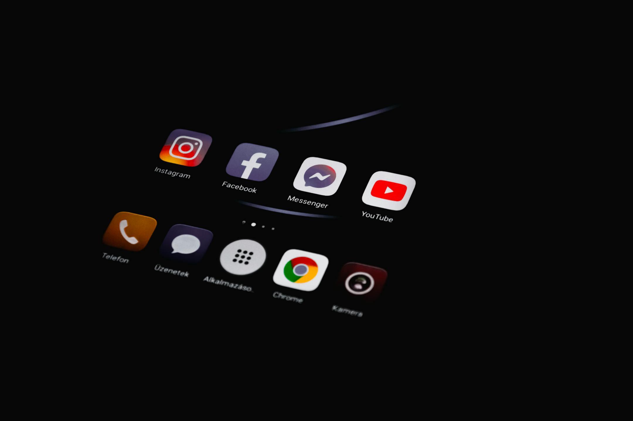 Close-up of smartphone displaying popular social media apps in dim lighting.