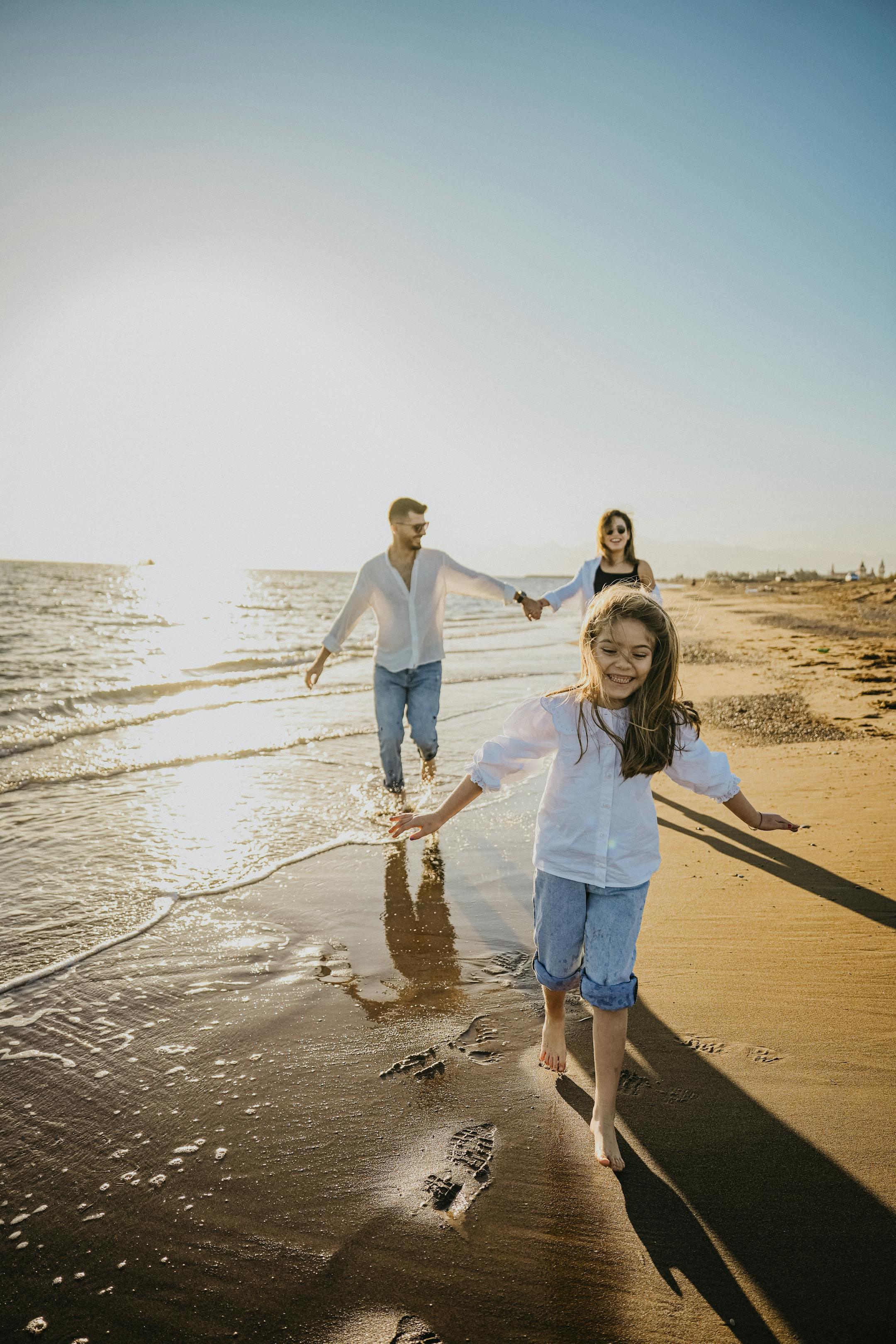 A happy family walking along the beach during a sunny sunset, enjoying a relaxing day together.