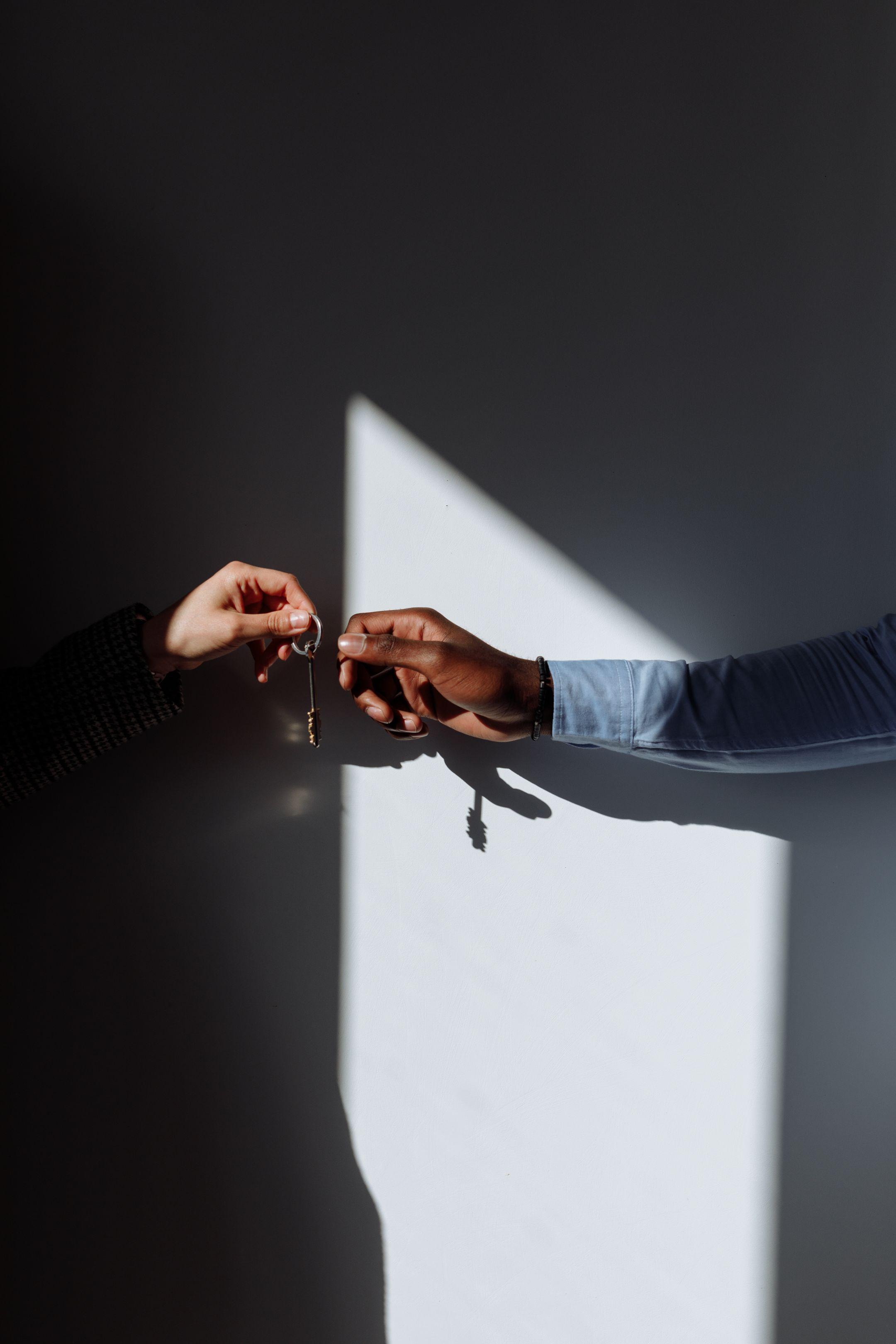 A symbolic handover of keys in a dimly lit room, representing change or agreement.