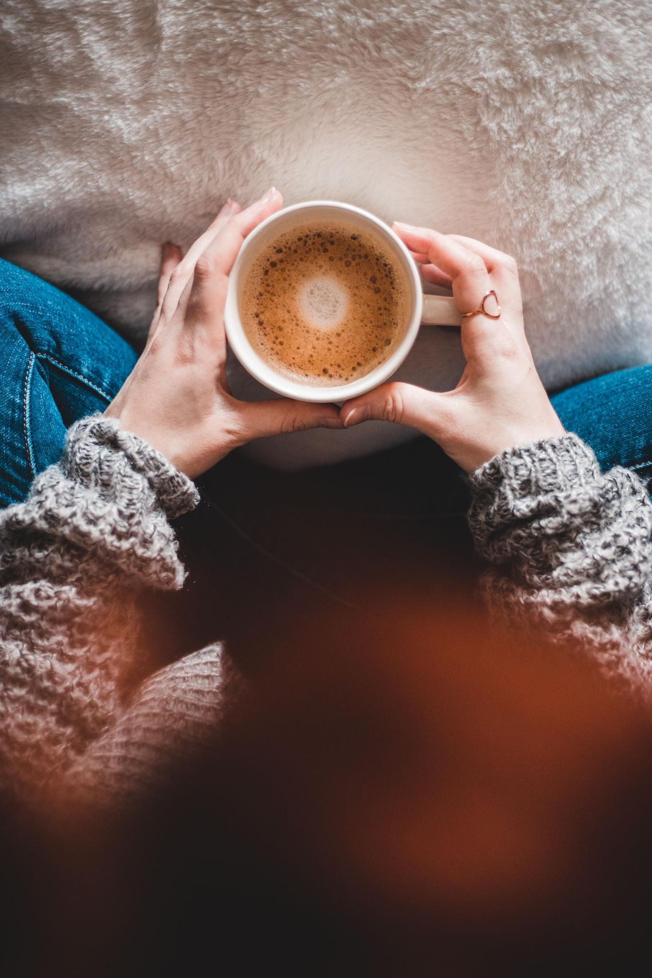 A woman holding a warm cup of coffee, creating a cozy and relaxed atmosphere.