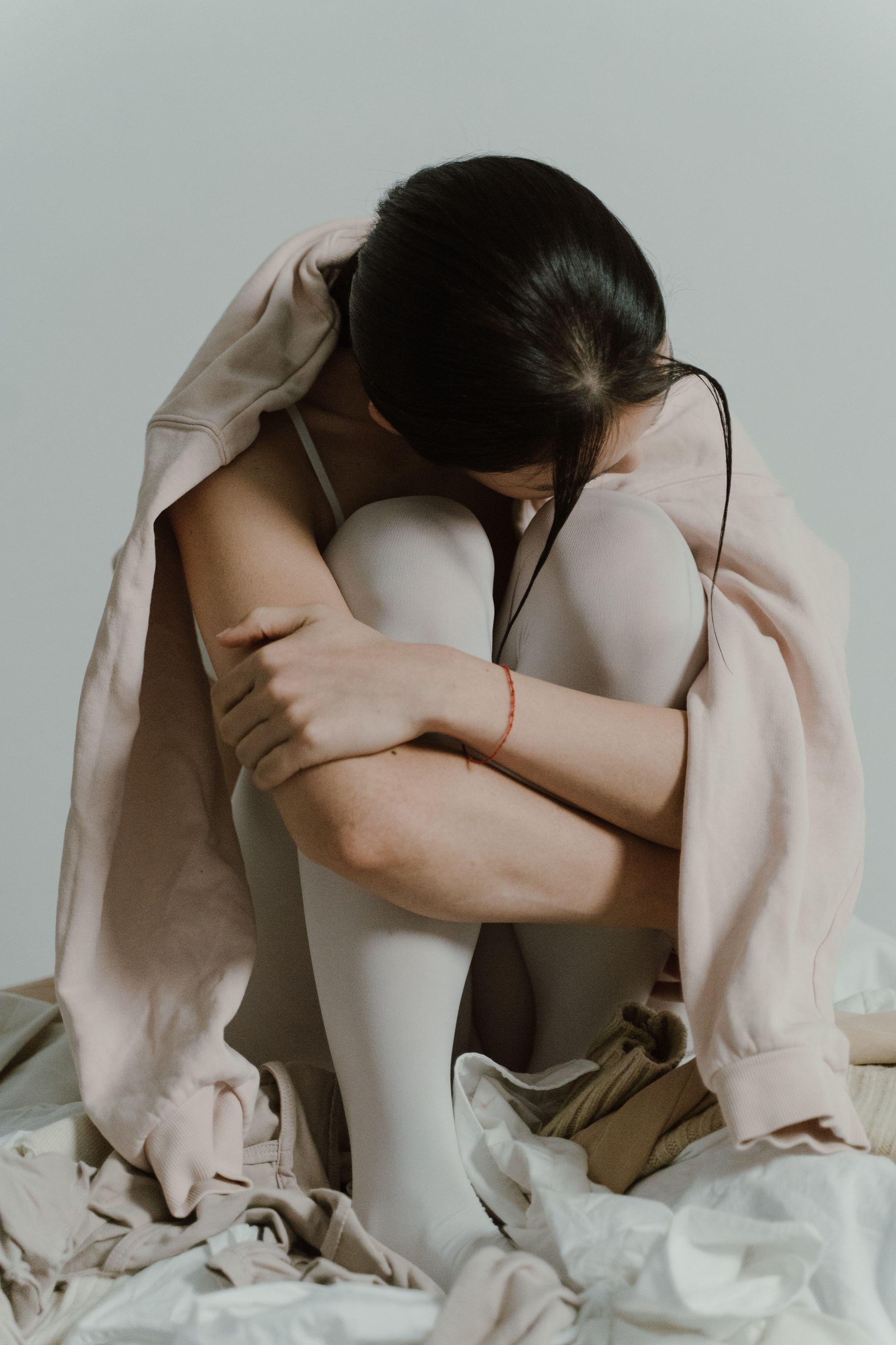 Woman sitting with knees embraced, expressing solitude and introspection.