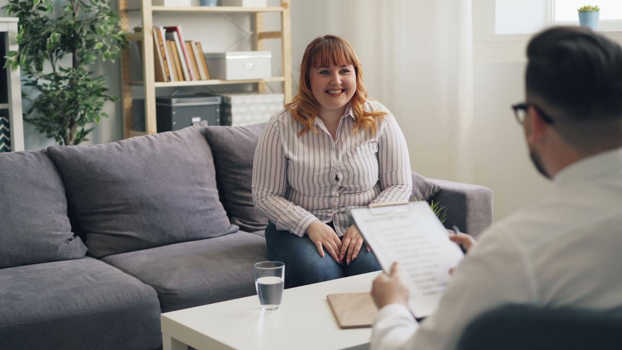 A cheerful woman discussing with her therapist during a consultation in a cozy office setting.