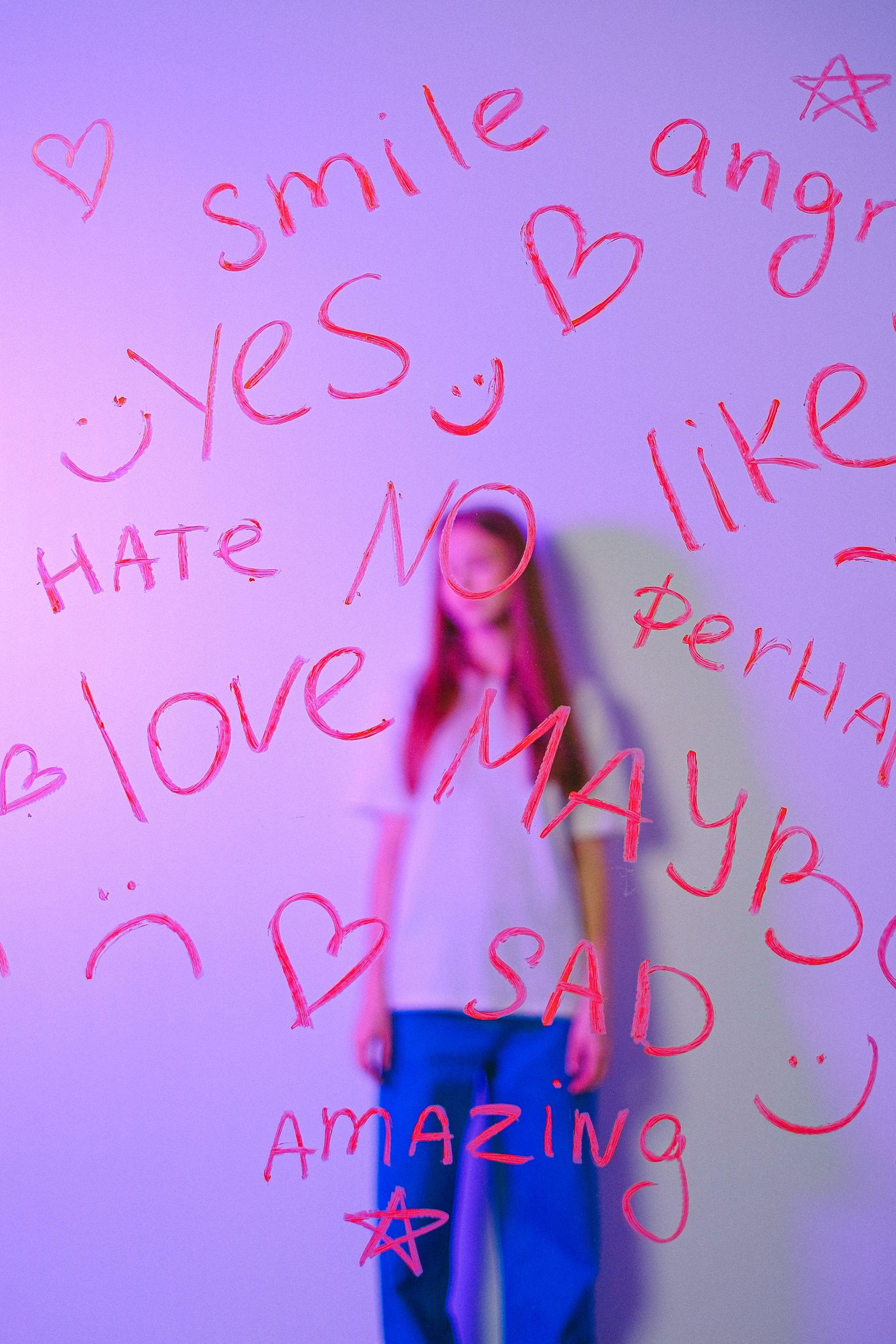 Teen girl behind a glass panel with words like smile, love, and amazing written in pink.