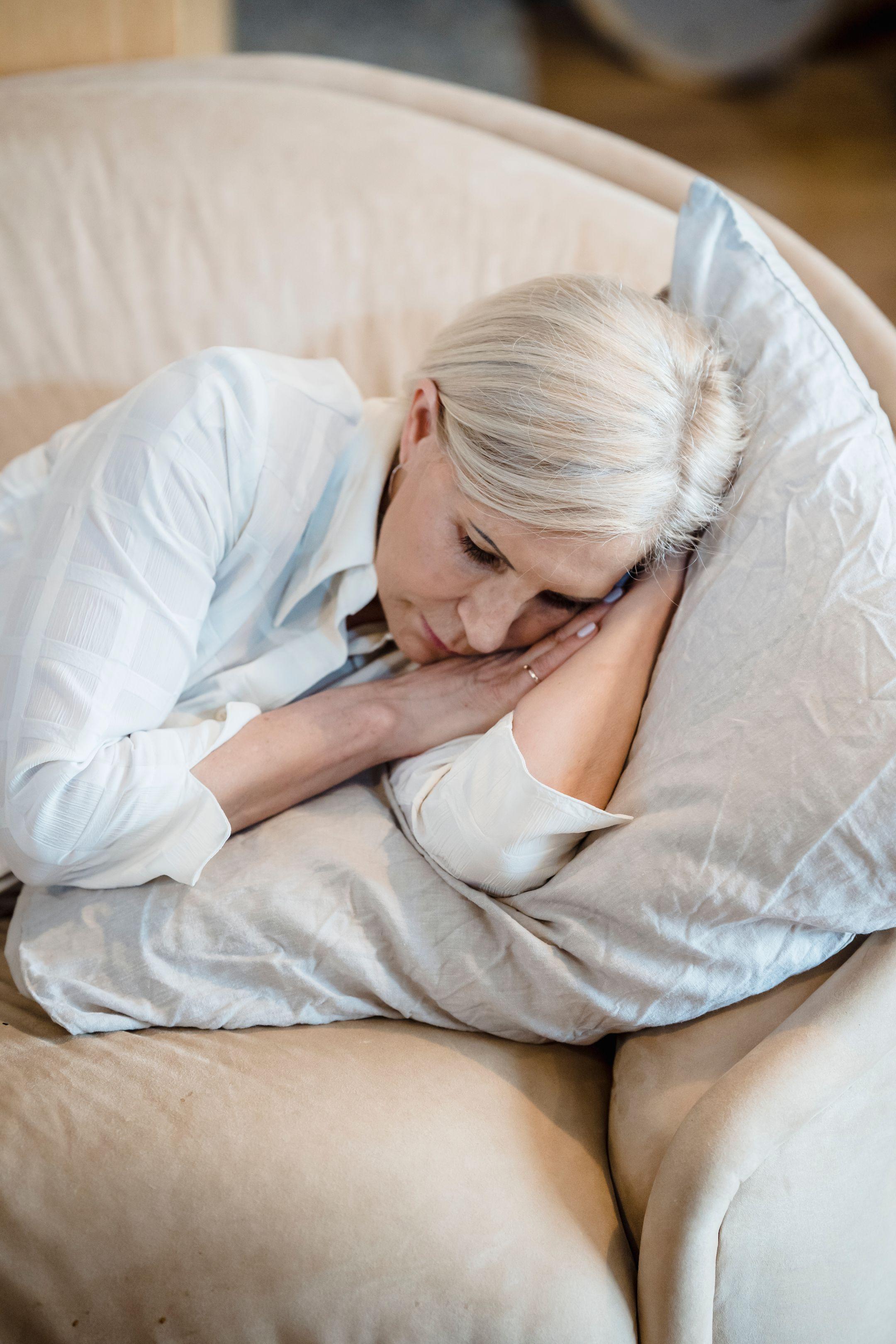 A serene adult resting on a cozy couch with a pillow, creating a tranquil atmosphere.