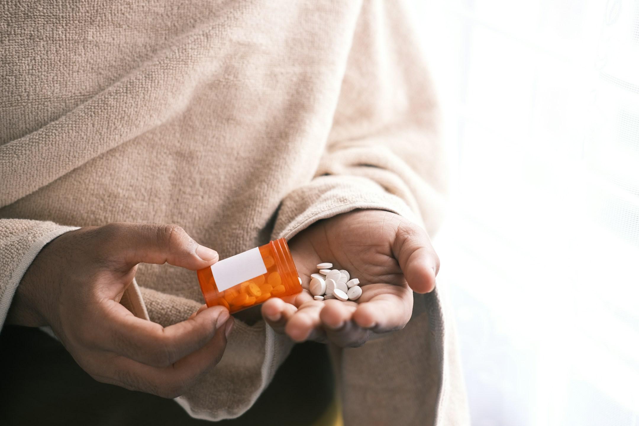 man's hand with pills spilled out of the container .