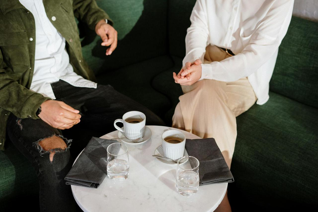 A couple enjoys coffee together in a stylish café setting, engaging in conversation.
