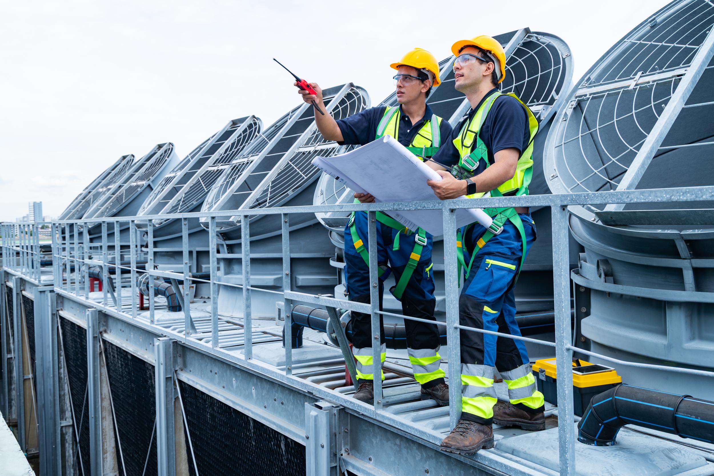 engineers-reviewing-blueprints-on-rooftop-hvac-sit-2026-01-11-10-12-19-utc.jpg