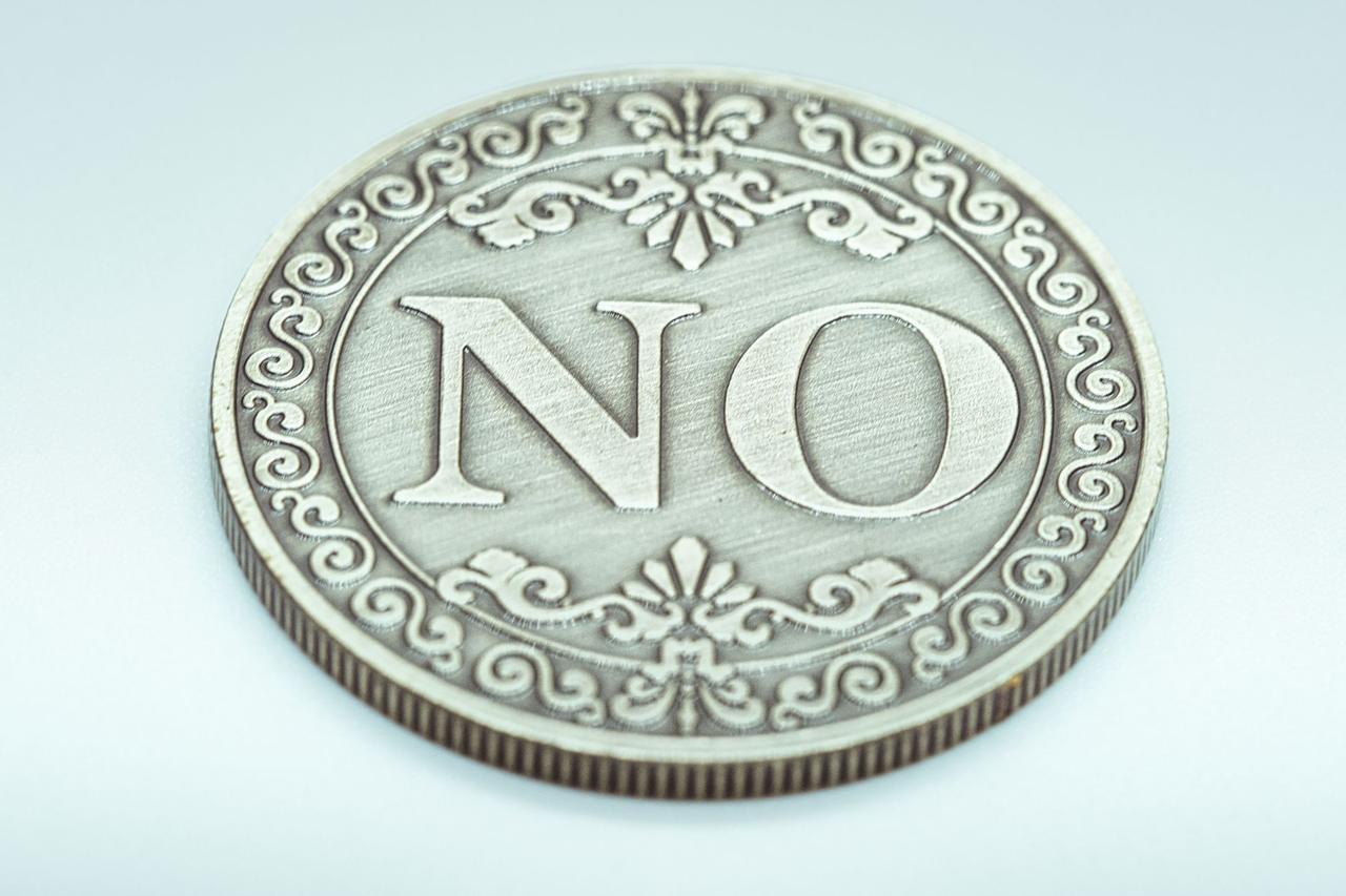 Intricate metal coin engraved with 'NO', symbolizing resistance or refusal.