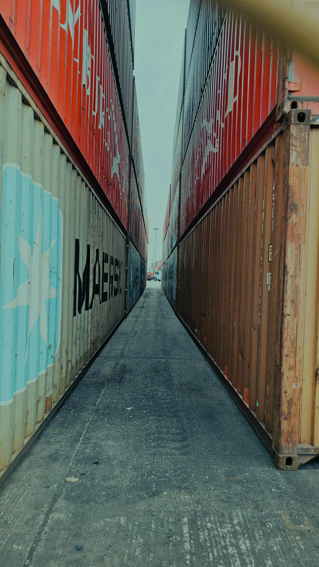 View down a narrow passage between colorful stacked shipping containers.