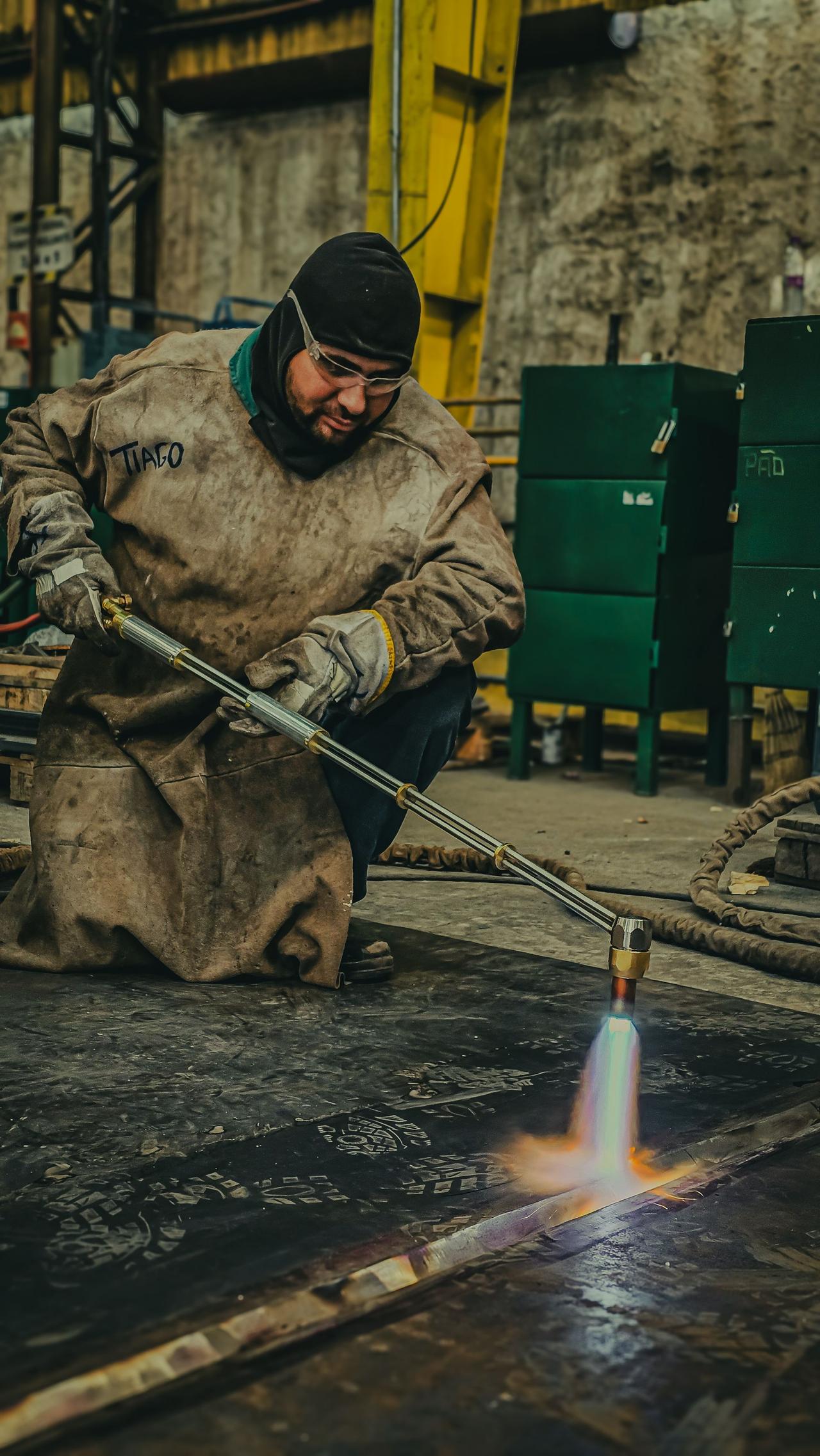 Skilled welding technician operating a blowtorch in an industrial workshop setting.