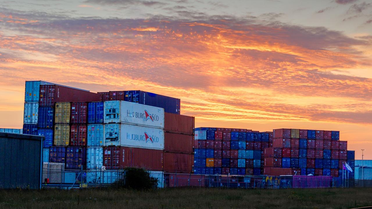 Colorful shipping containers stacked at sunset in Rotterdam port.