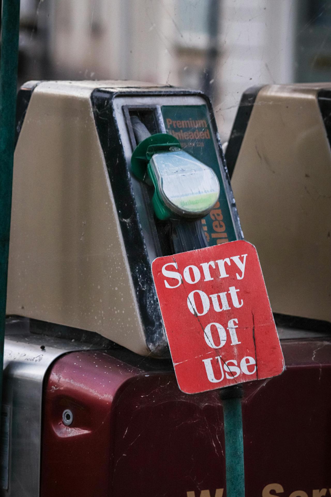 Close-up image of a gasoline pump marked with an out of use sign, emphasizing fuel shortage.