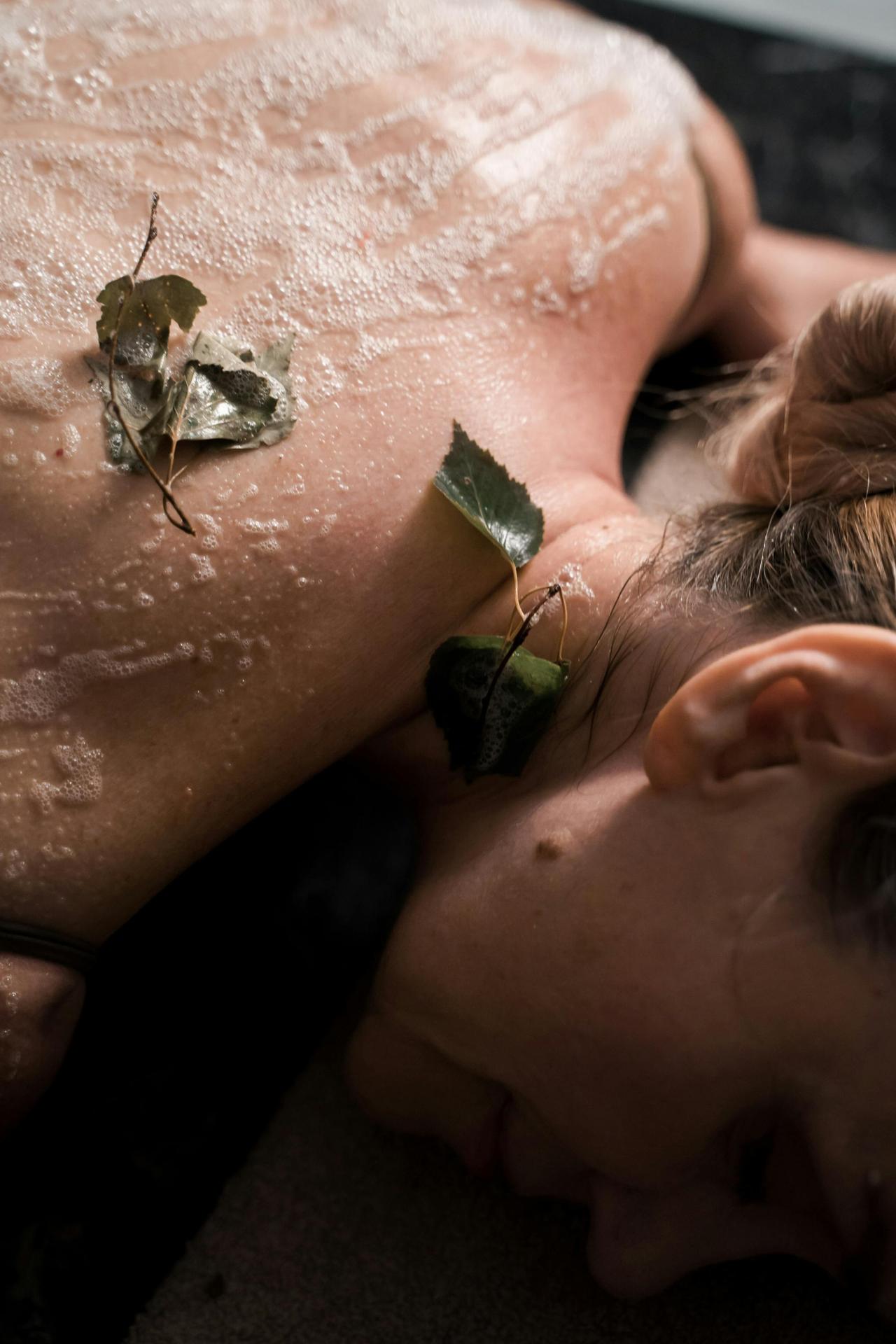 Close-up of a woman enjoying a relaxing spa treatment with natural leaves and exfoliation.