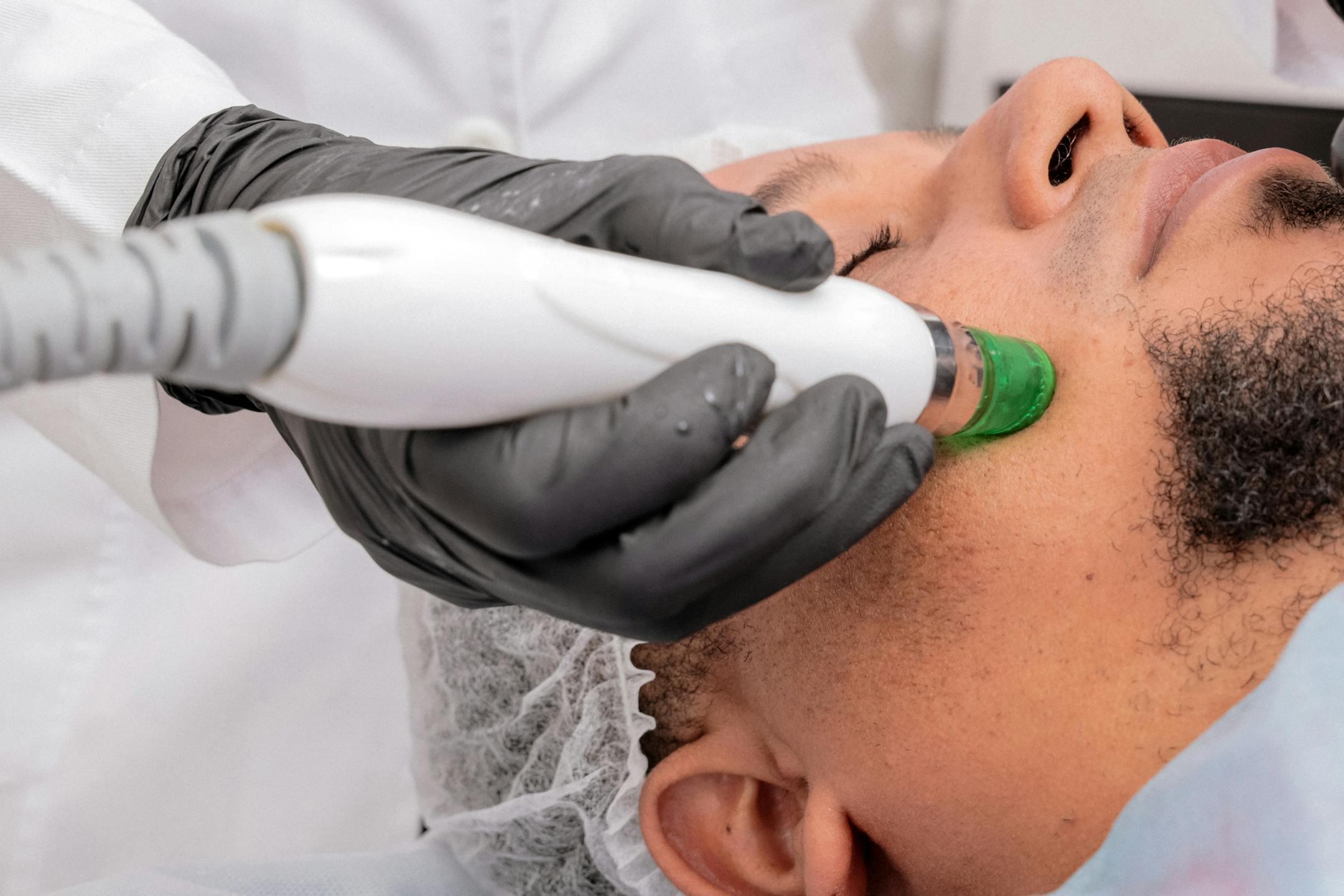 A close-up of a man receiving a professional skincare treatment in a clinical setting.