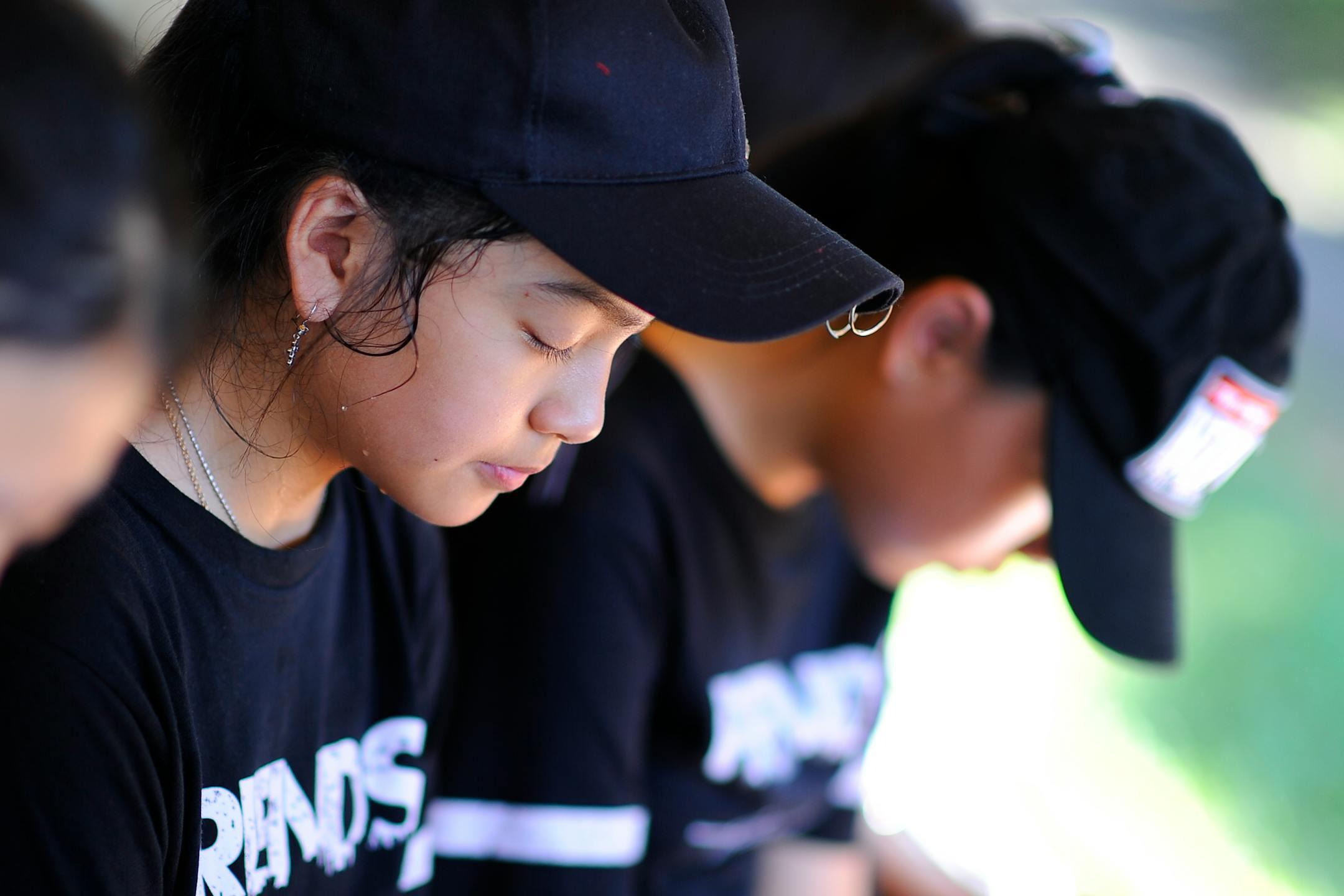 Close-up of teenagers wearing caps and t-shirts, eyes closed in contemplation.