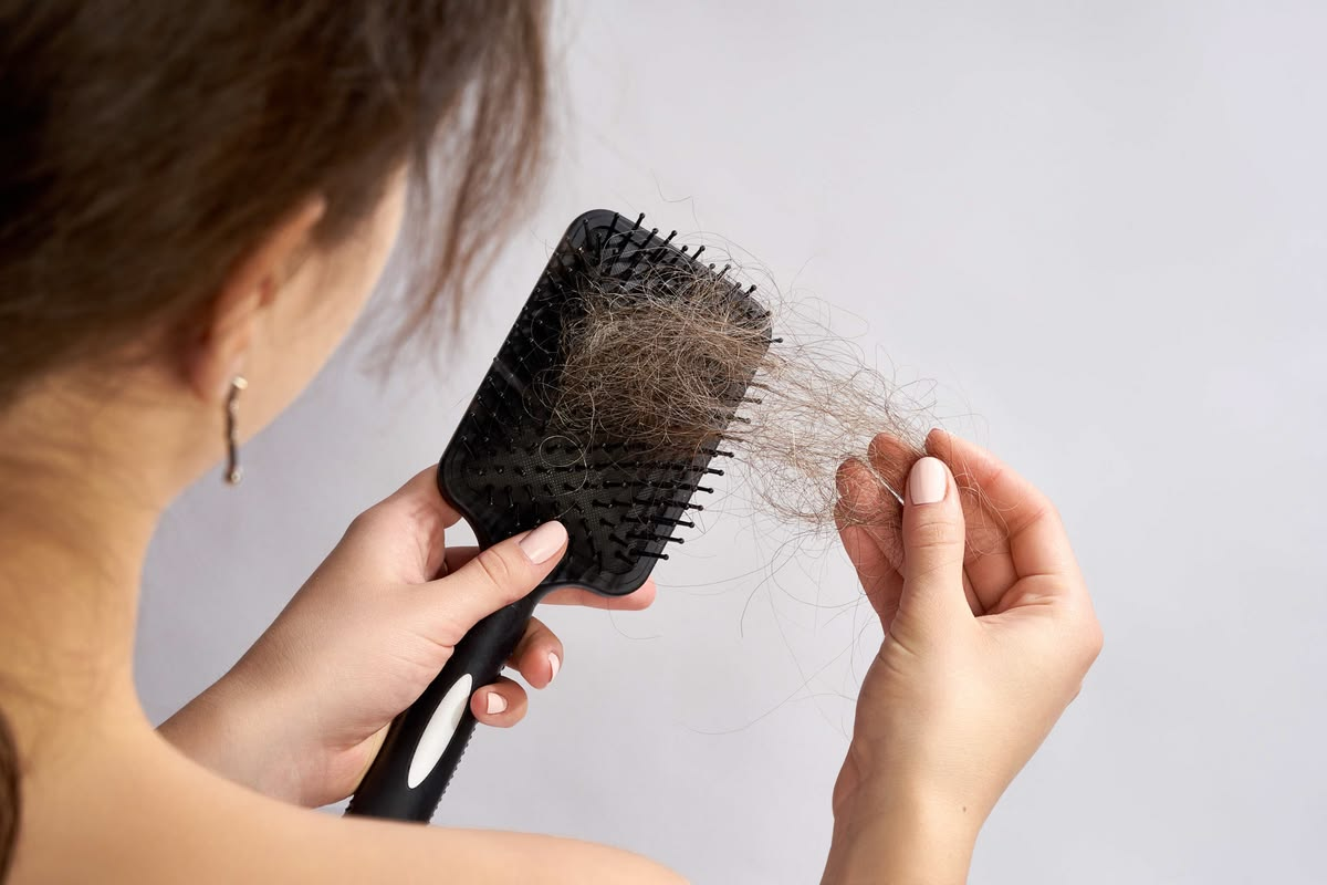 Natural hair care flat-lay with wooden comb, nourishing oil, aloe leaf, and rosemary