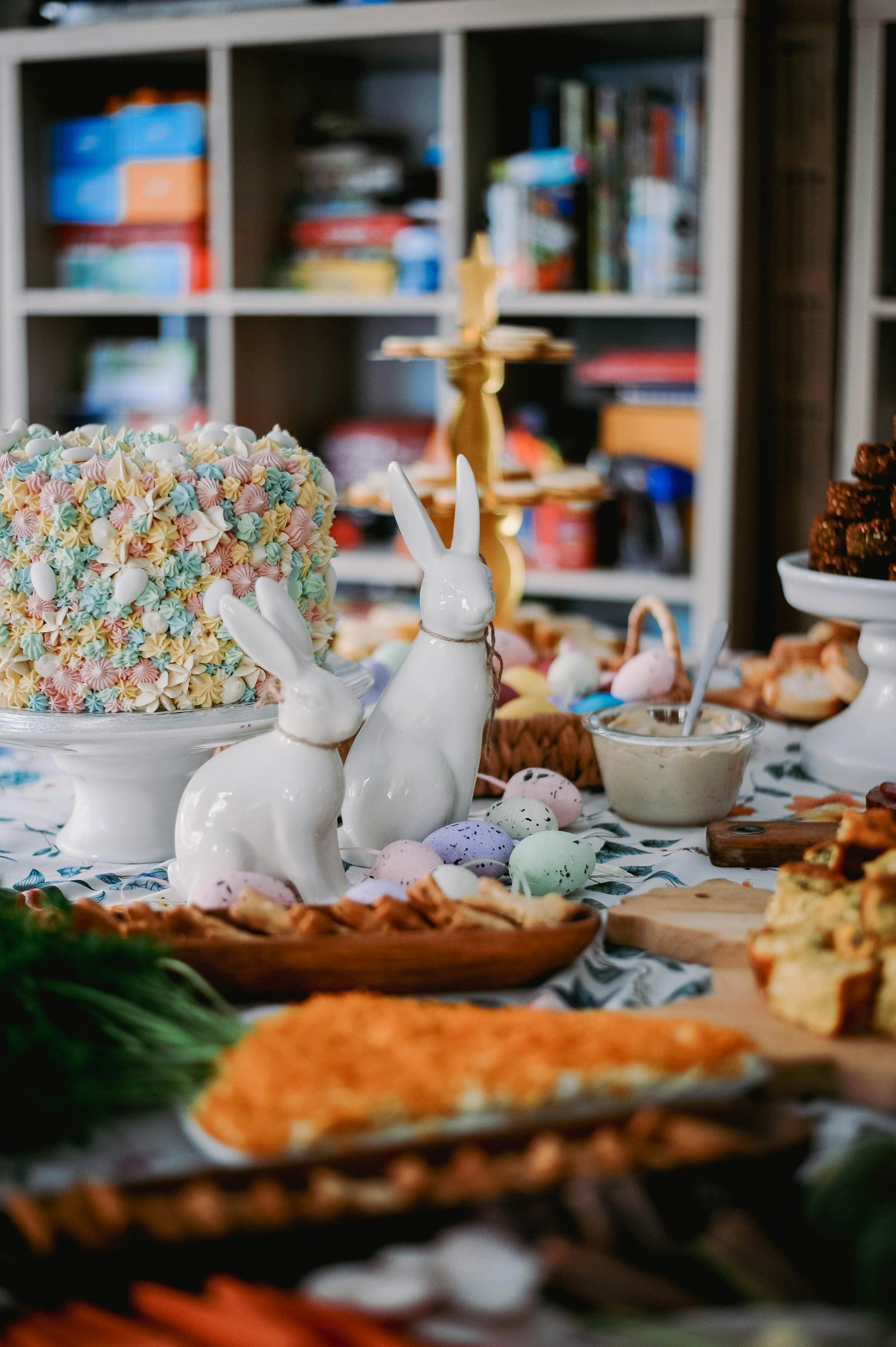 Festive Easter table setting with decorative rabbits, cake, and colorful pastries.