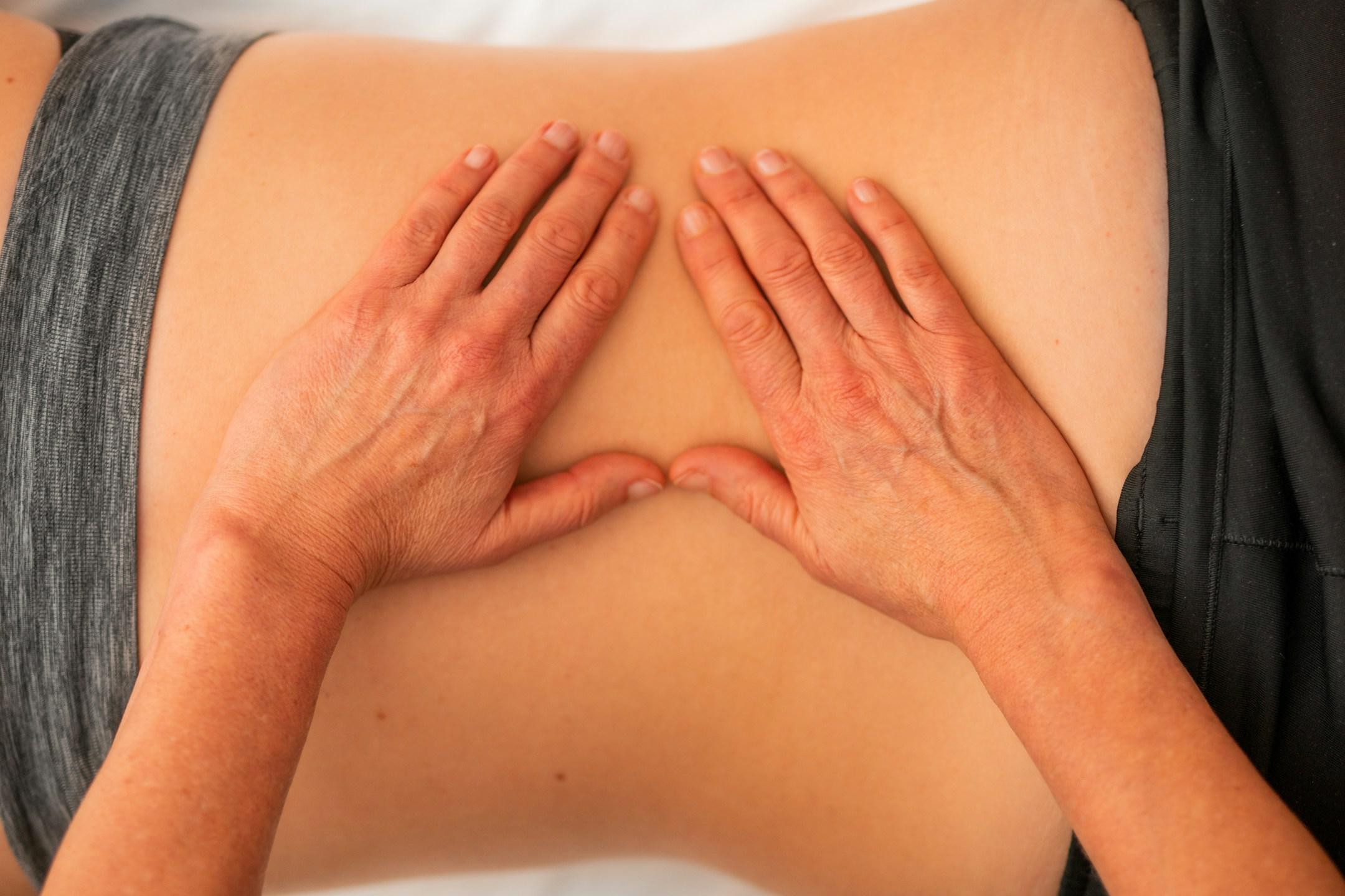 Ostheopathy with two hands formed in a triangle on the back of a woman