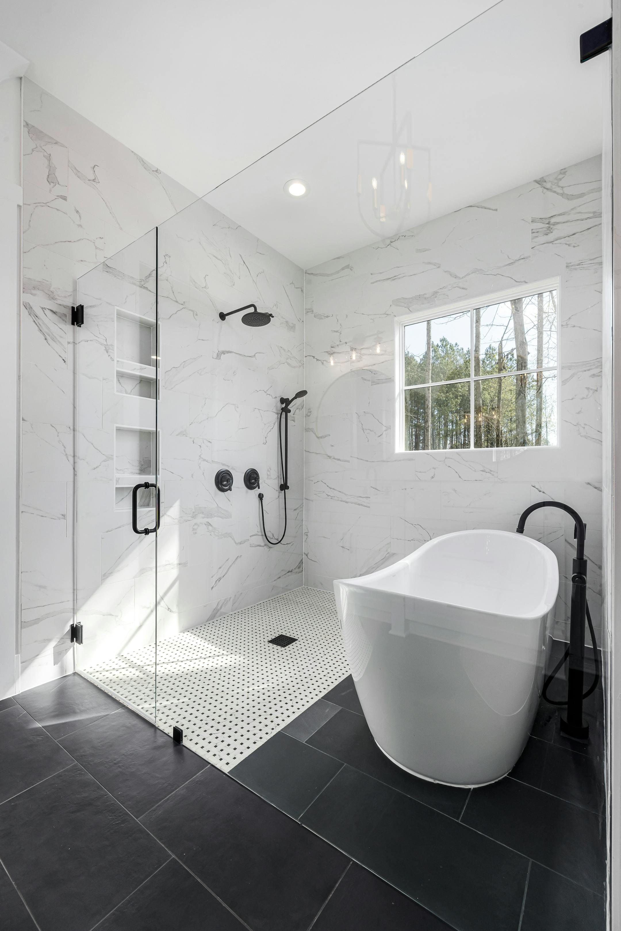 Sleek white bathroom with freestanding tub, glass shower, and natural lighting.