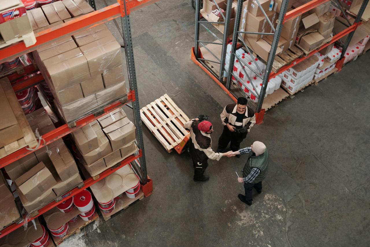 High angle view of workers shaking hands in a warehouse, symbolizing teamwork and logistics.