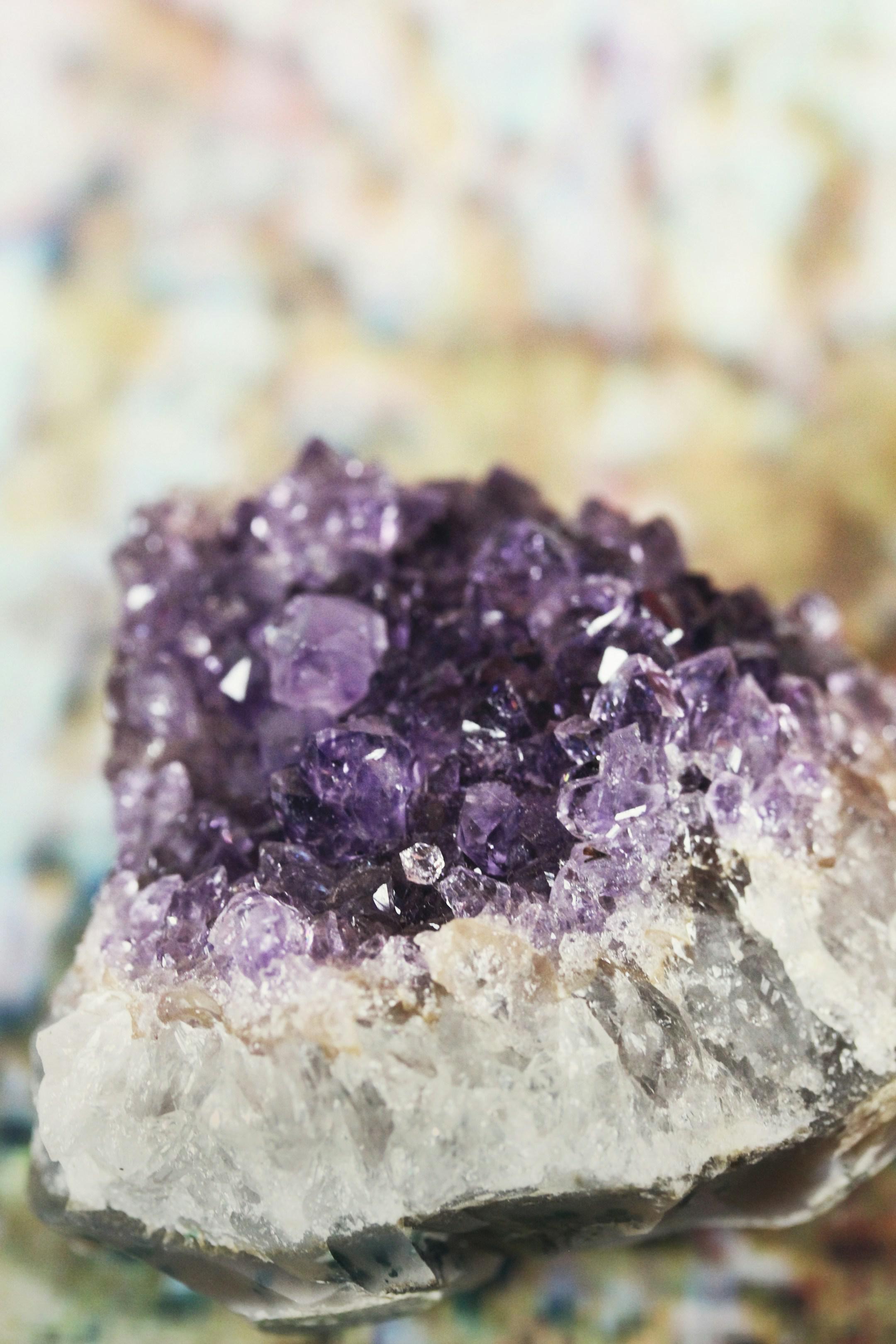 A beautifully vibrant crystal amethyst cut geode sits on a neutral background. Gem stone crystals are deep purple and quartz base. Light reflects off the prisms created by the pointy crystal, commonly used in new age practices and spiritual rituals.
