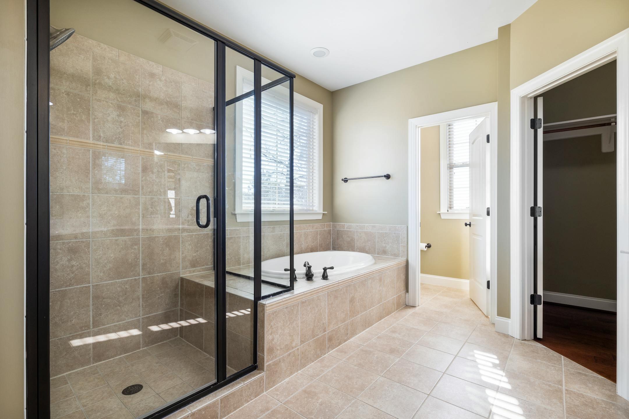 Spacious and bright bathroom featuring glass shower and built-in bathtub with natural light.