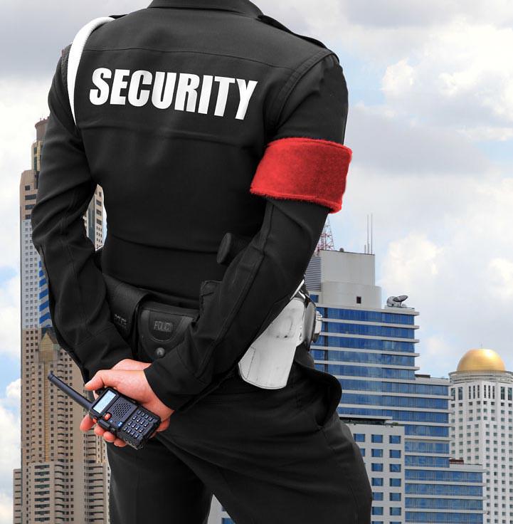 A security guard standing at attention facing a cityscape. Learning how to renew  your security license in Ontario is a commitment to your community.