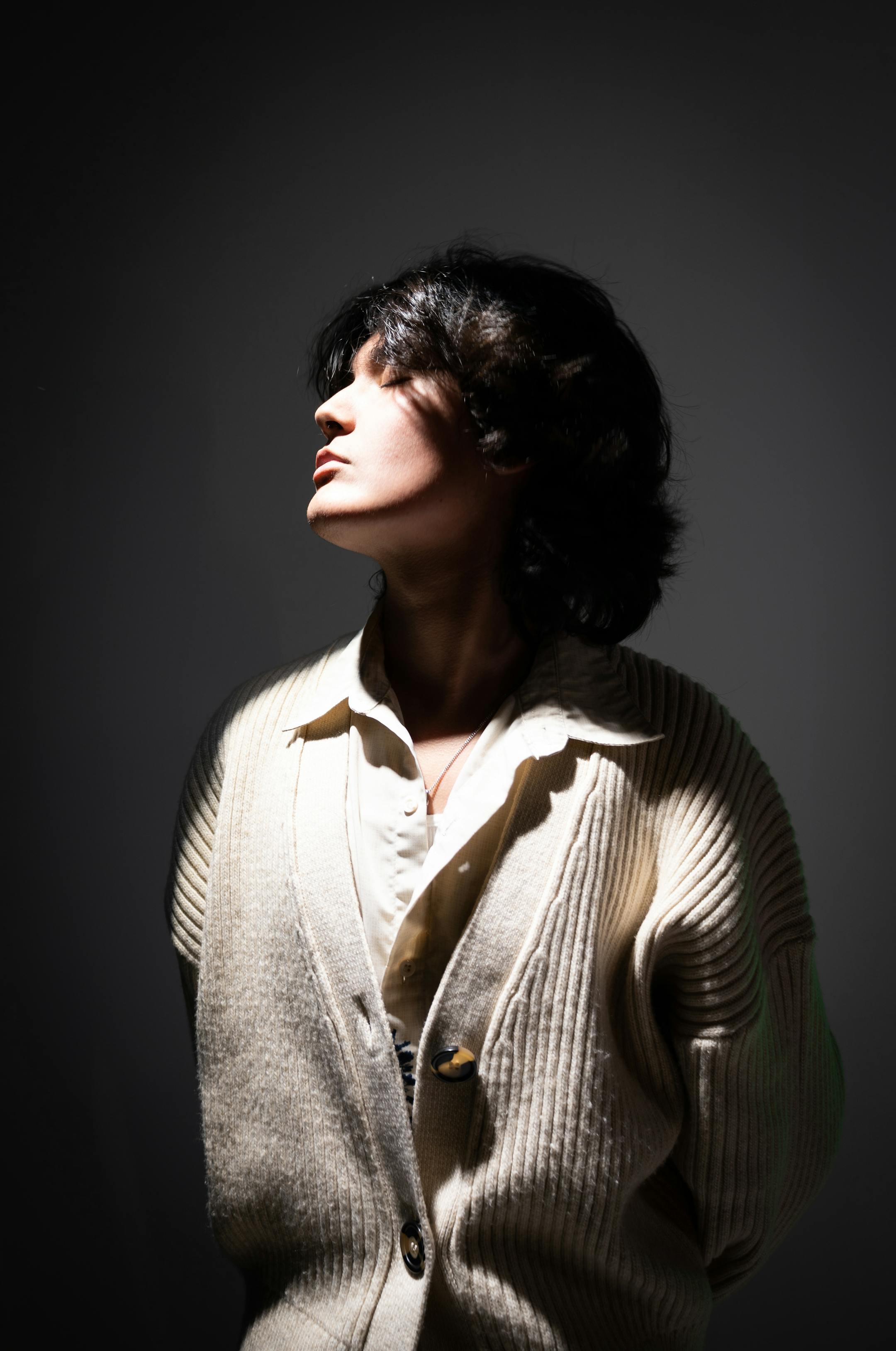 Dramatic studio portrait of a woman in elegant attire with moody lighting.