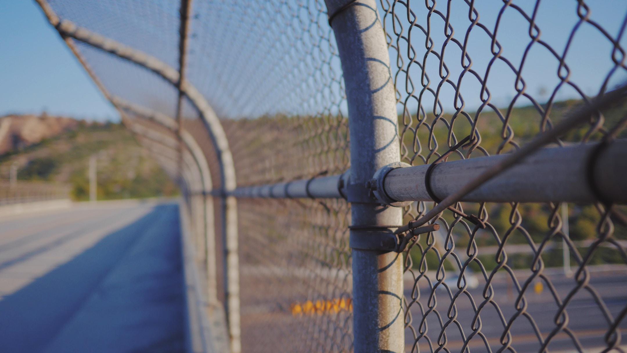 A fence along an overpass above a highway.
