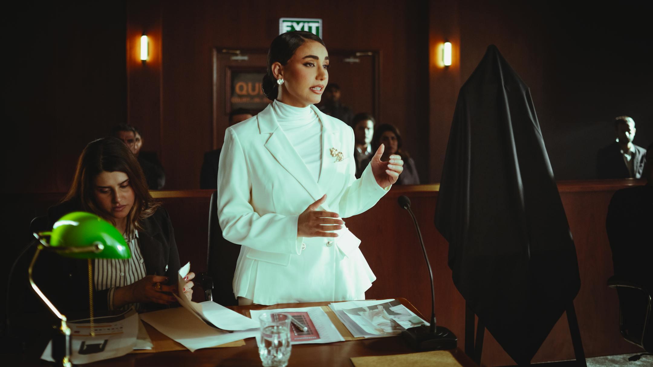 Confident woman in white suit presenting a case in an elegant courtroom setting.