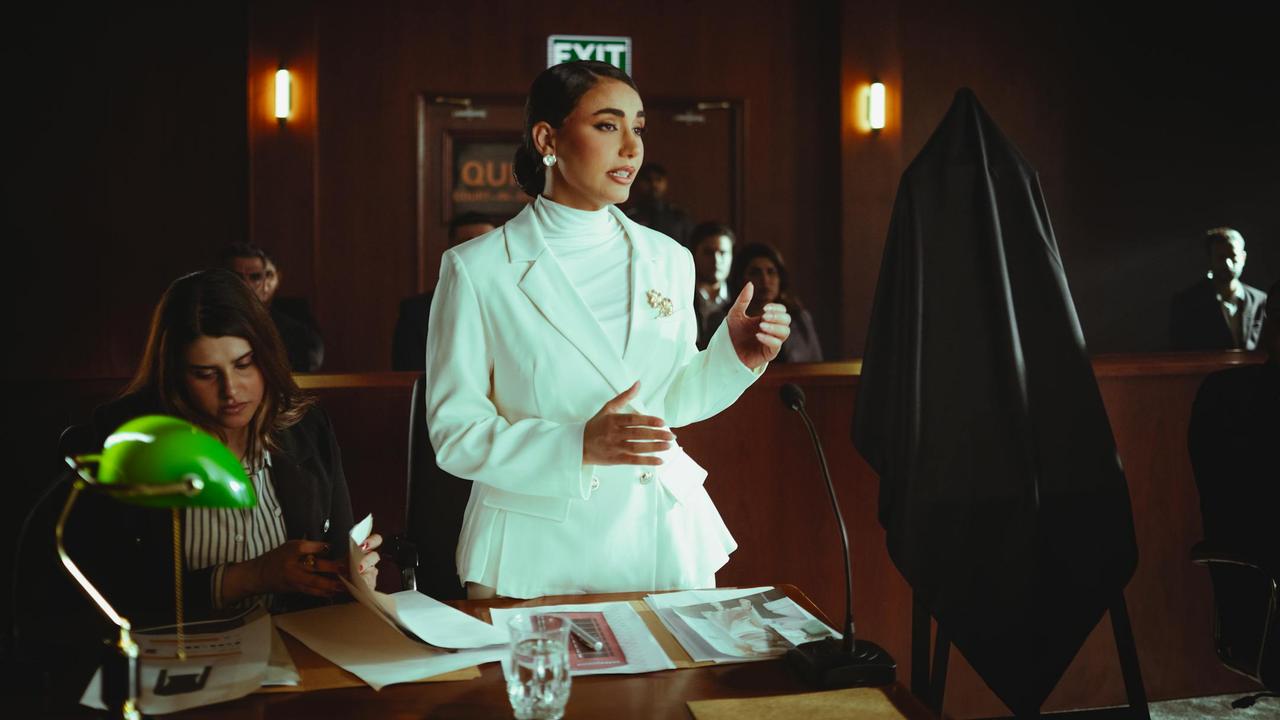 Confident woman in white suit presenting a case in an elegant courtroom setting.