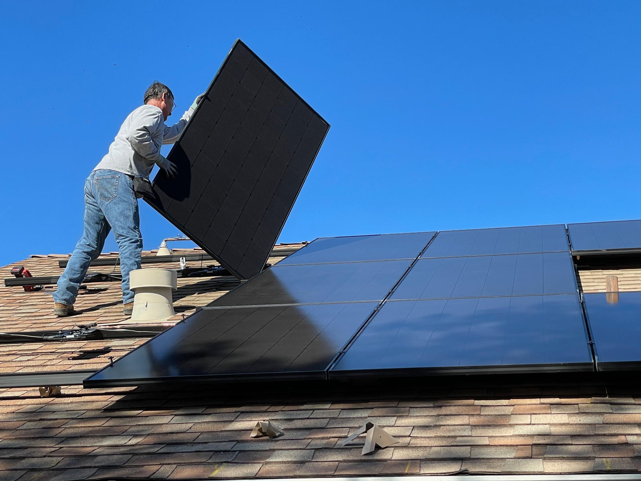 Image of a man on a roof performing solar system service maintenance.