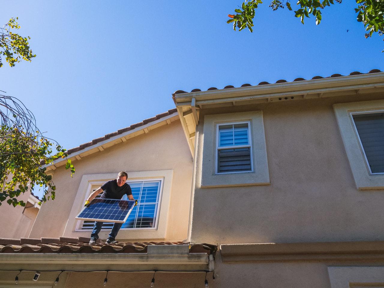 person installing solar panel on roof of residential property