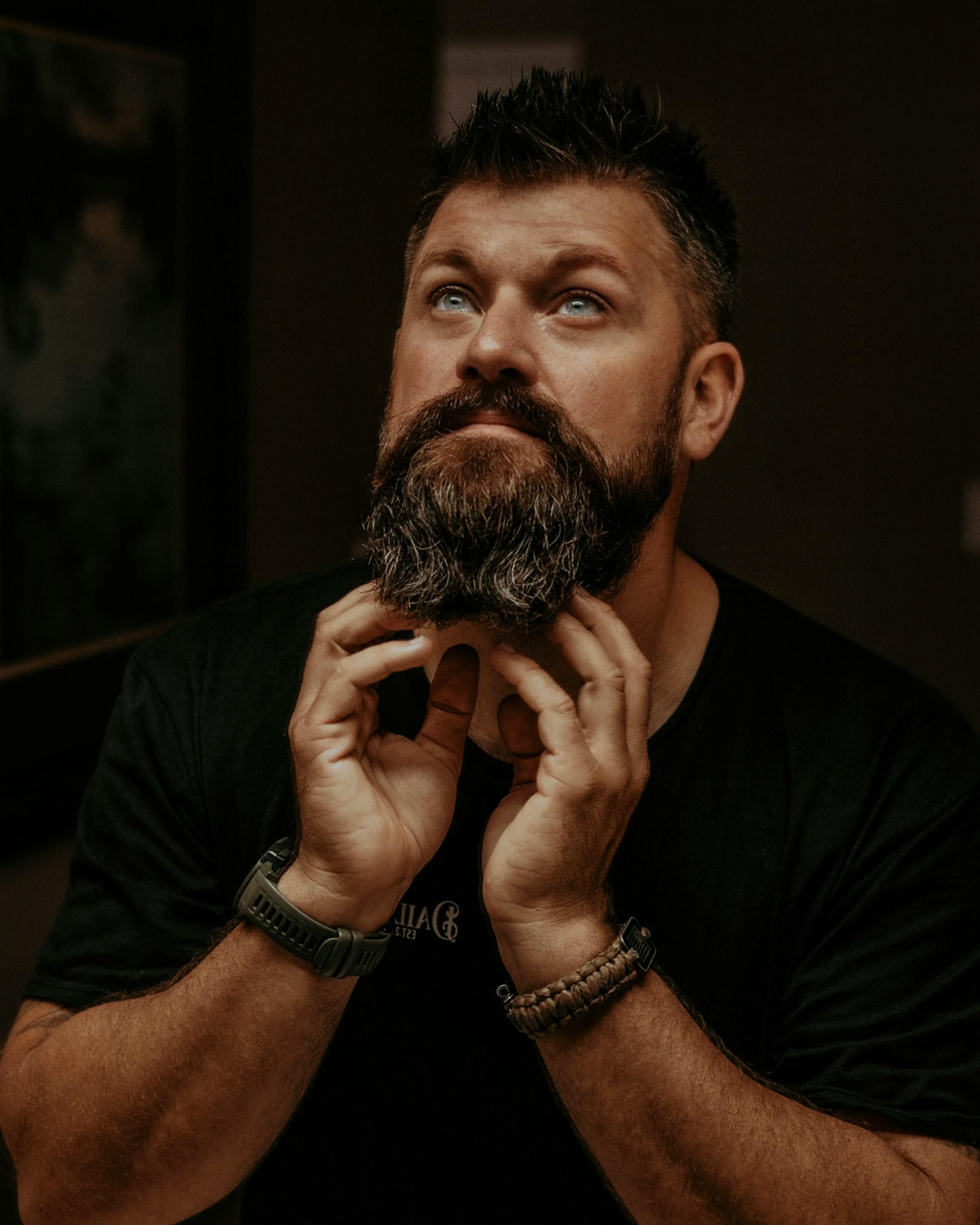 Candid photo of a bearded man applying Daily Grind beard oil to his beard. Photo by Lance Reis / KickassDesigns on IG