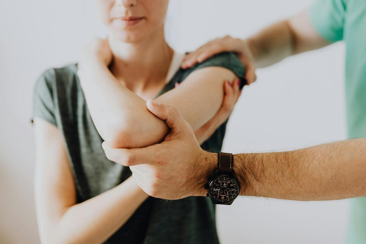 A chiropractor adjusting a patient's arm in a clinic setting, focusing on health and care.