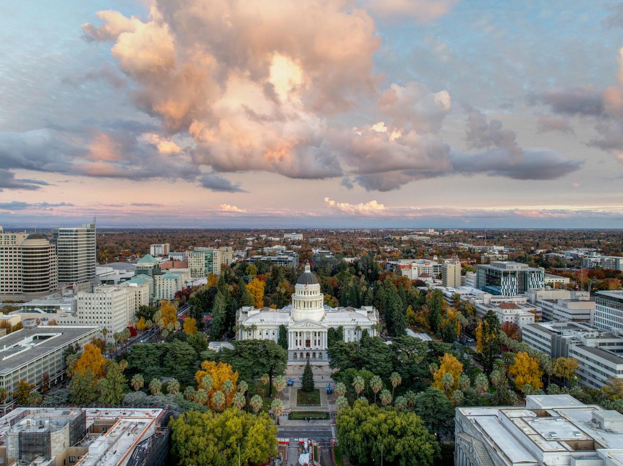 Stunning aerial view of the California State Capitol during a beautiful sunset with vibrant clouds.