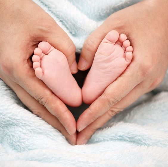 A newborn baby's feet held gently in an adult's hands