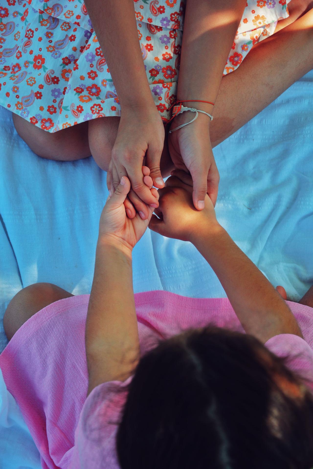Two girls sitting and holding hands, symbolizing friendship and emotional connection.