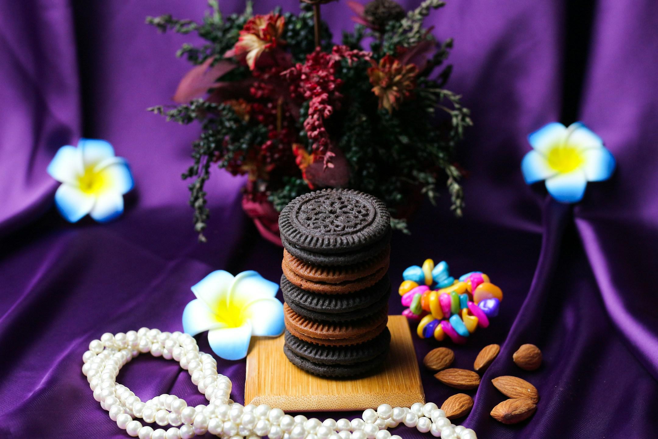 Delicious cookies and nuts with flowers with a purple cloth background and red roses and blue and yellow begonias