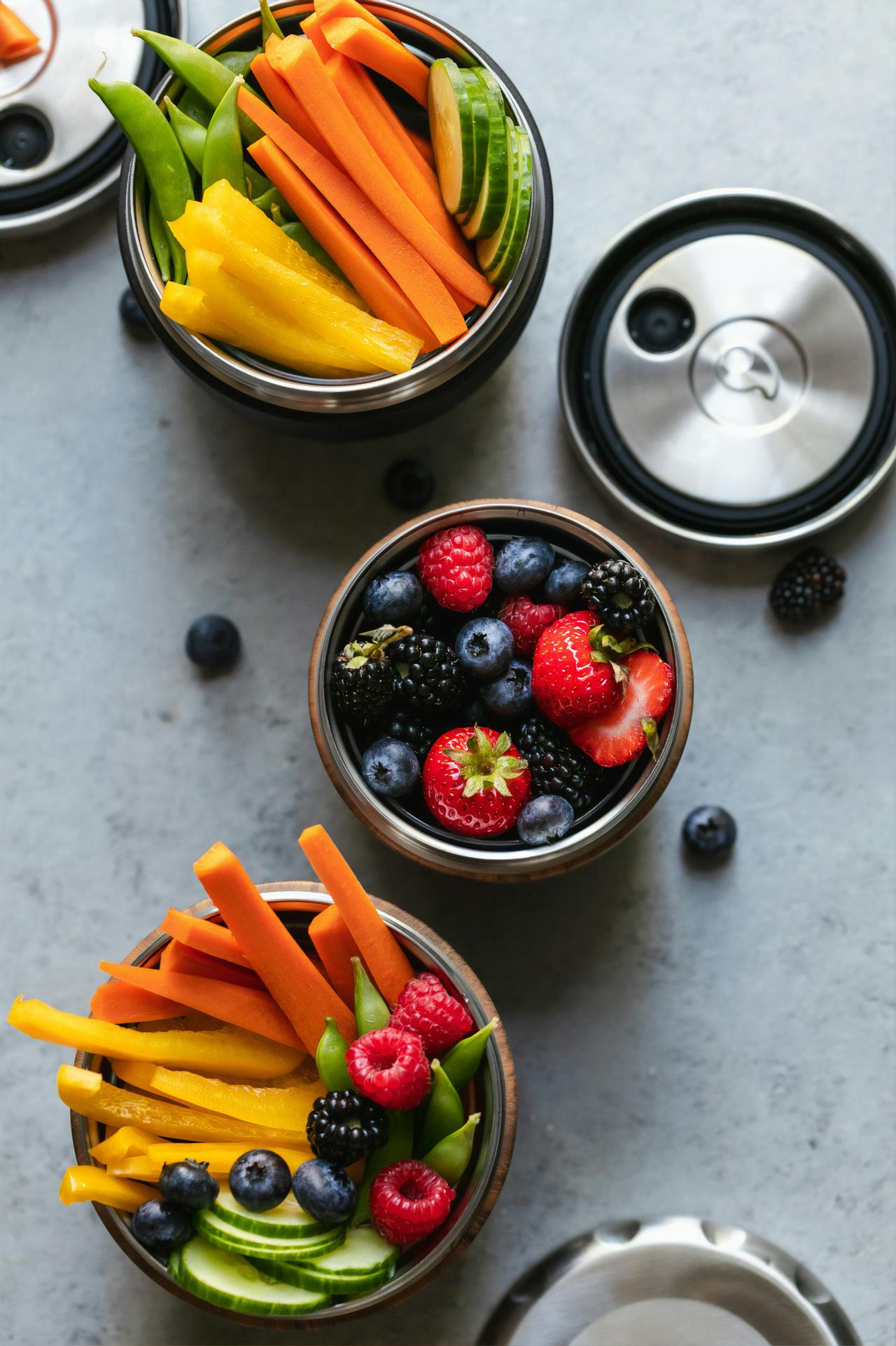 vibrant fruit and vegetable set up for snacking on a granite counter background, blue berries, strawberry, bell pepper, carrot, orange, yellow, green, blue red, raspberry