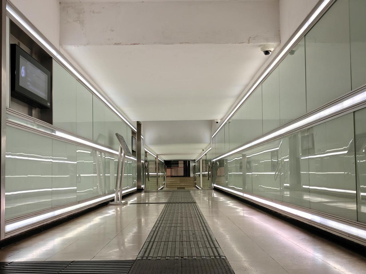 Spacious modern corridor with glass panels and bright lighting.