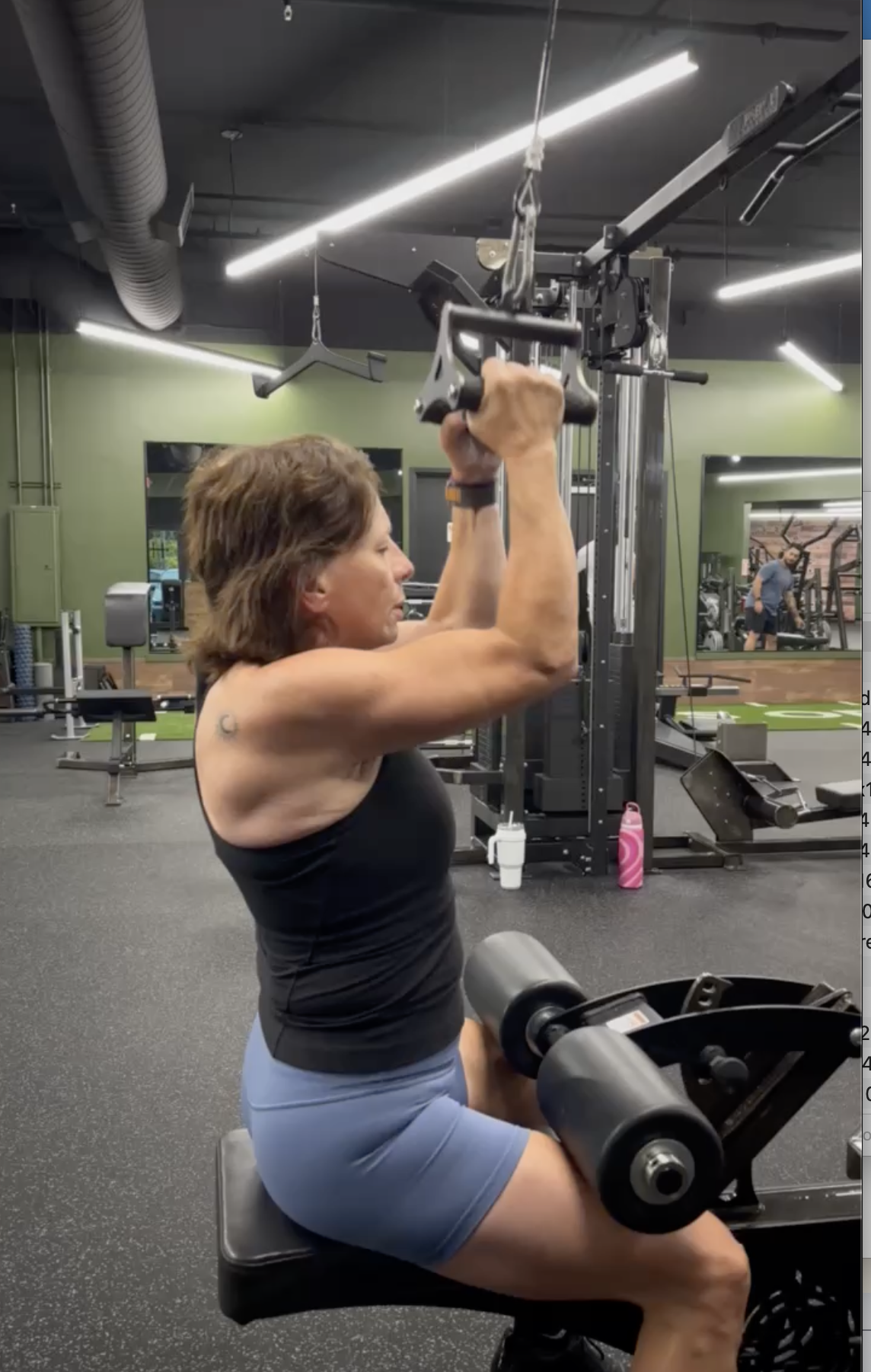 Woman performing cable machine exercise in a gym, demonstrating strength training