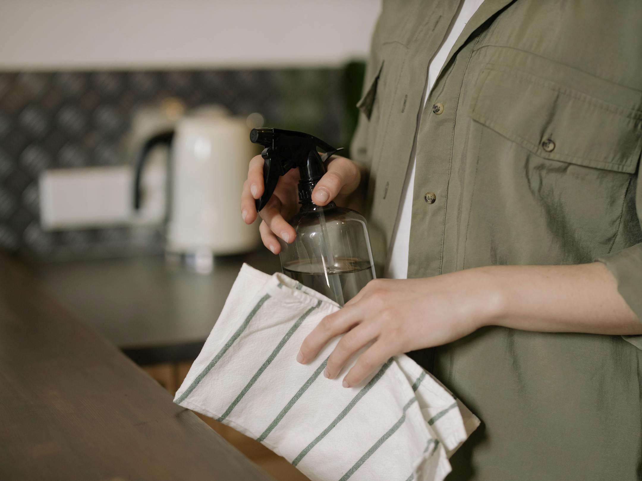A person cleaning a kitchen counters. Mystic Cleaning Co. uses non-toxic cleaners for healthier homes and a sustainable future.