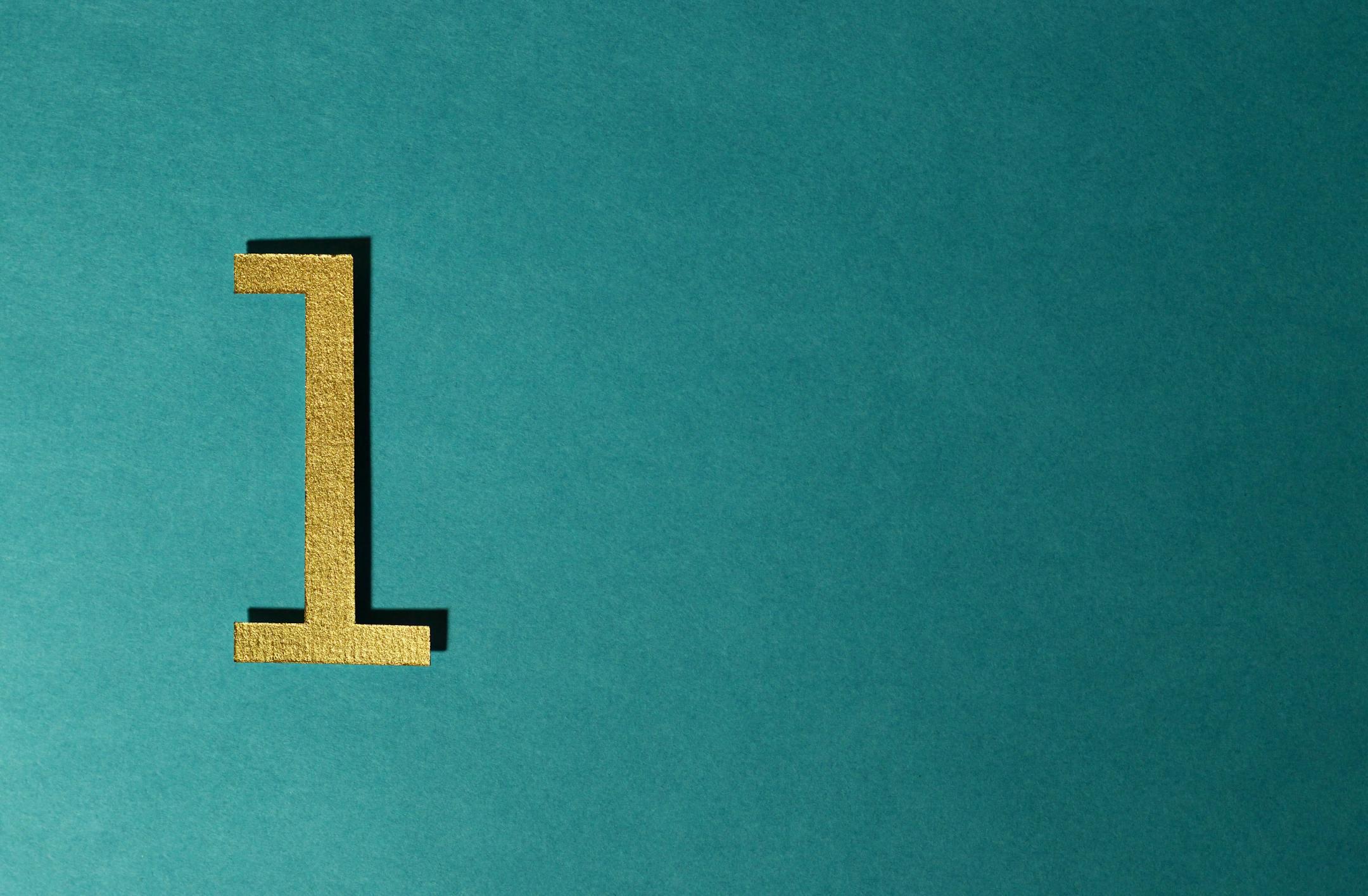 A gold number one on a teal background with ample copy space.