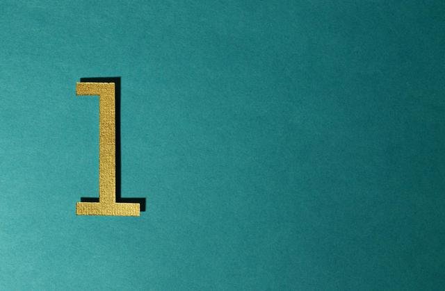 A gold number one on a teal background with ample copy space.