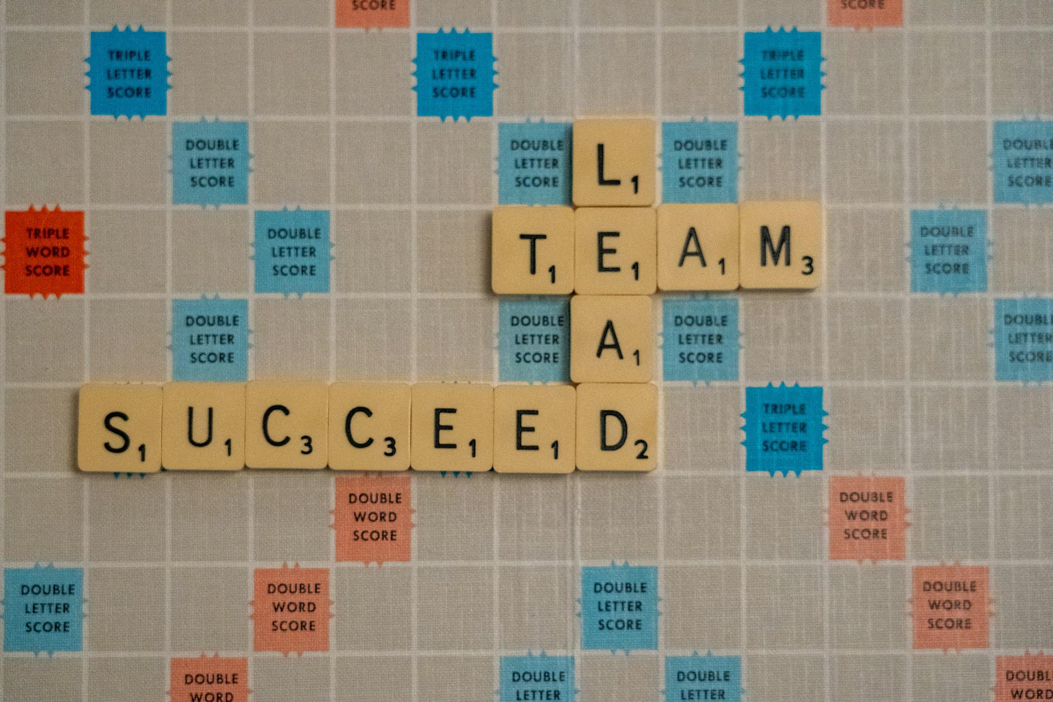 Team Lead Succeed, the title of a business book by Nick Fewings, Teamologist at Ngagementworks, spelled out in scrabble letters.