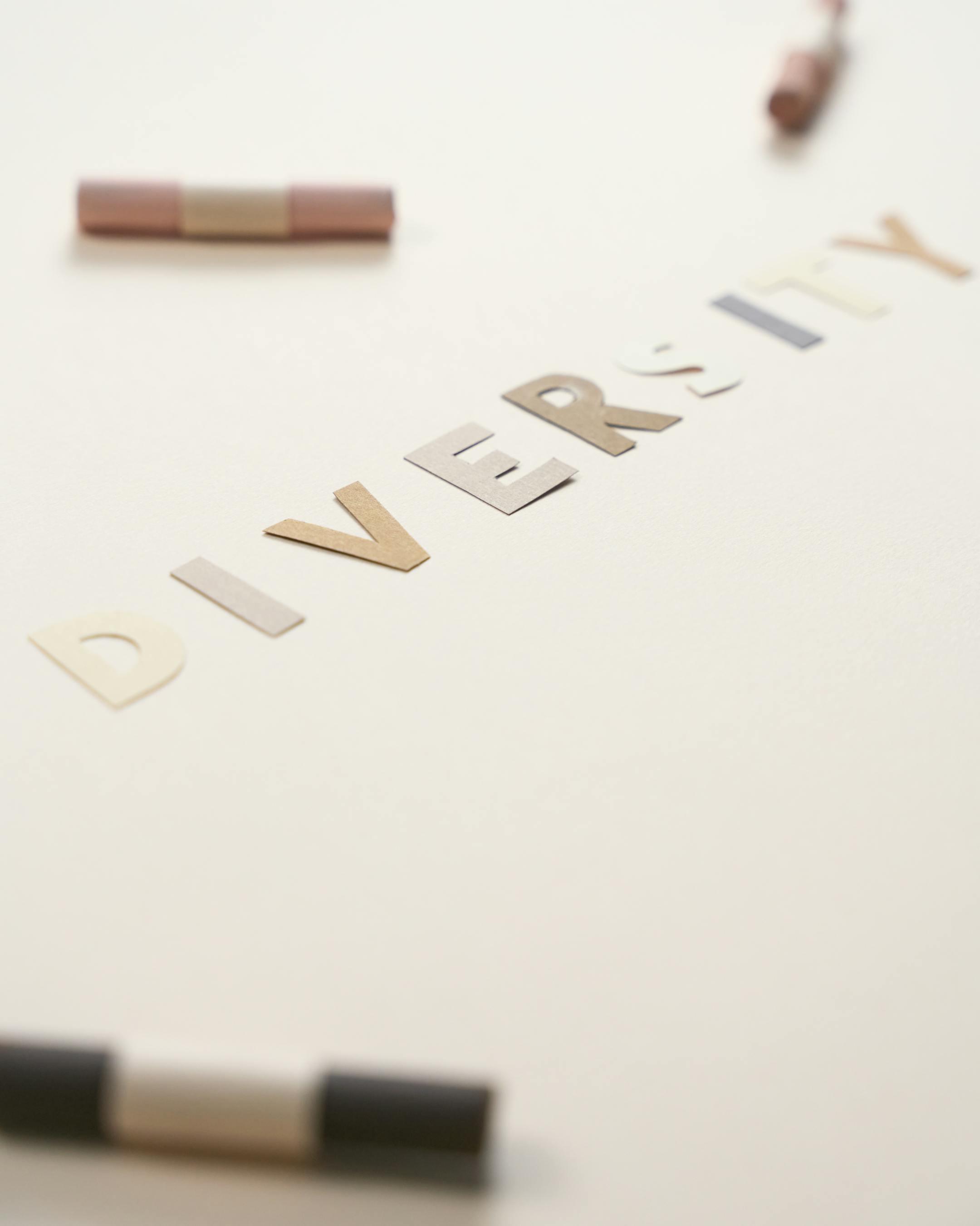 Artistic arrangement of the word "Diversity" using cut-out colored letters on a plain white background.