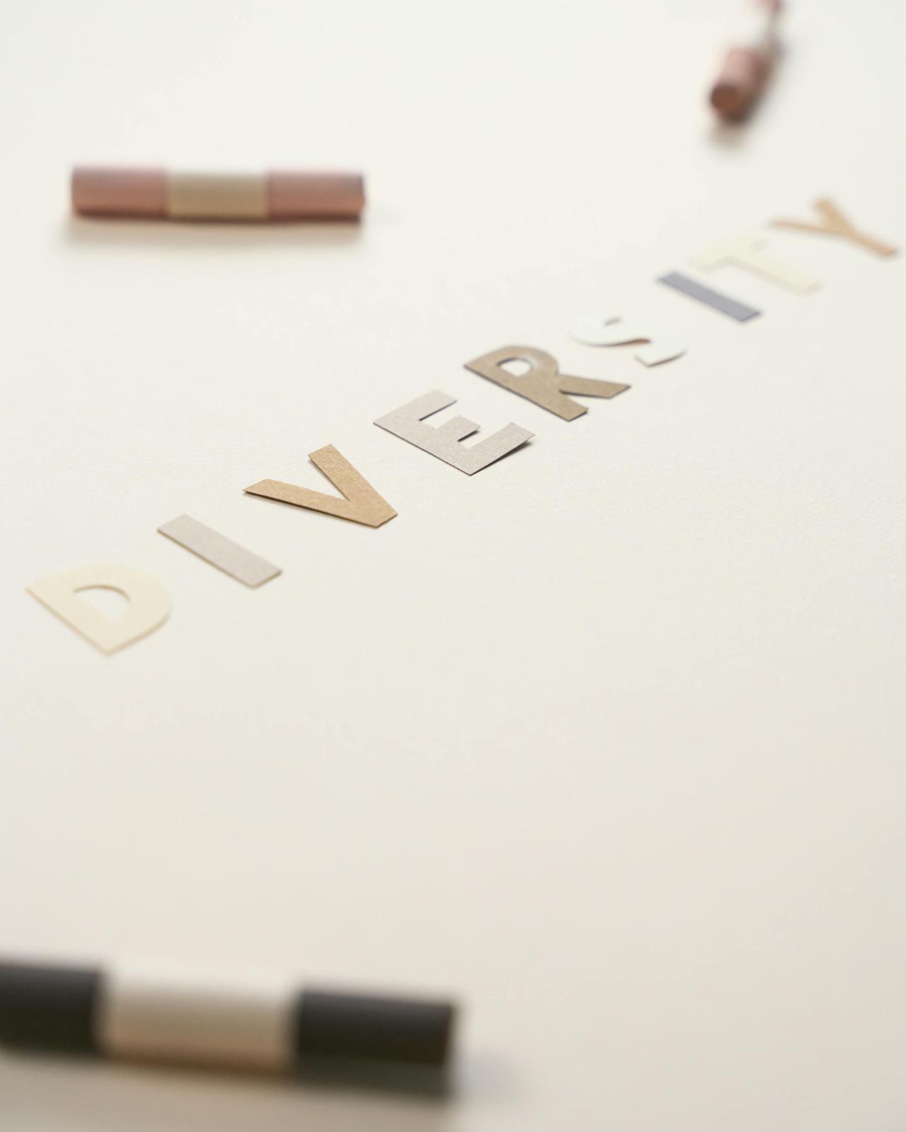 Artistic arrangement of the word "Diversity" using cut-out colored letters on a plain white background.