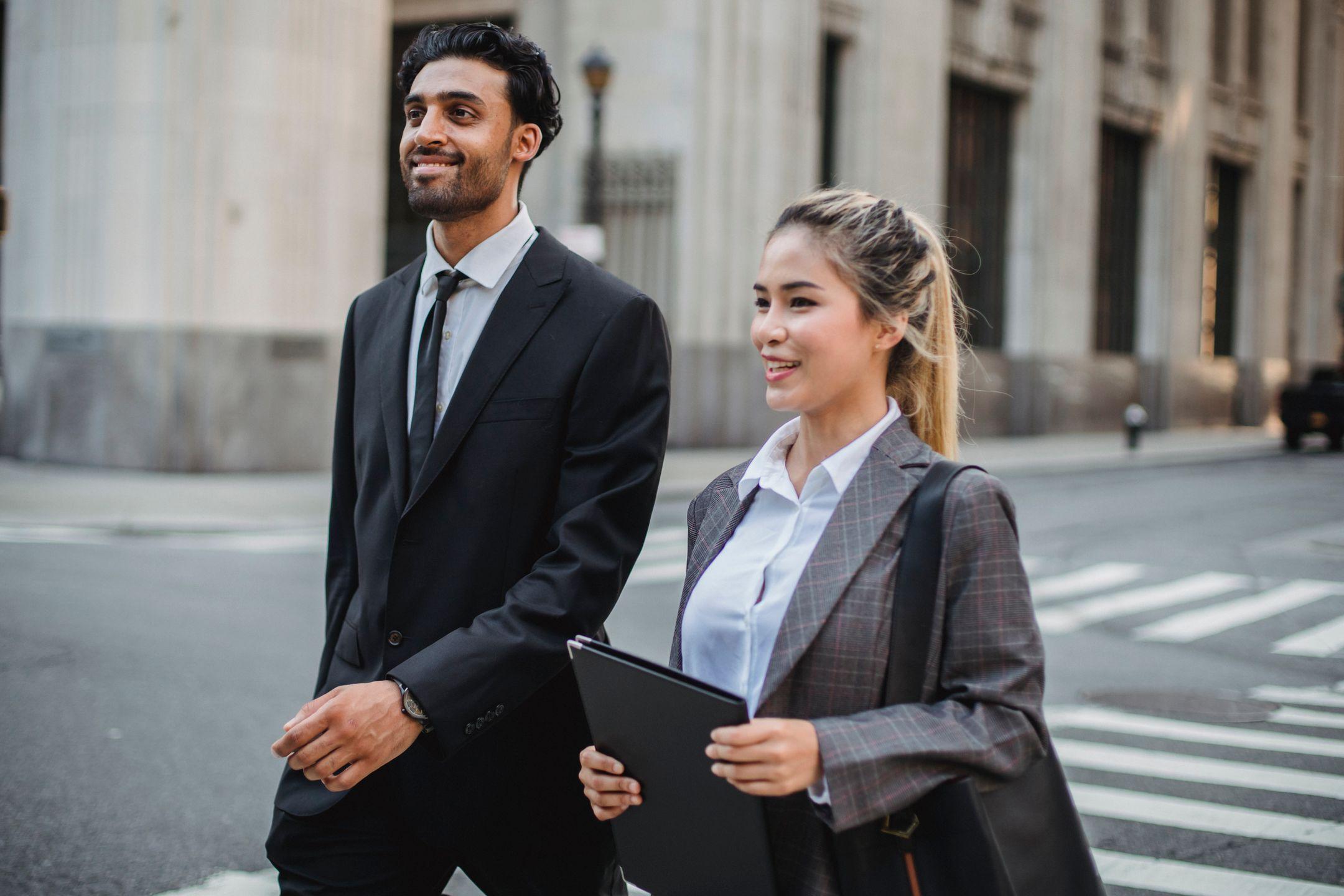 Business professionals in corporate attire walking confidently in an urban street setting.